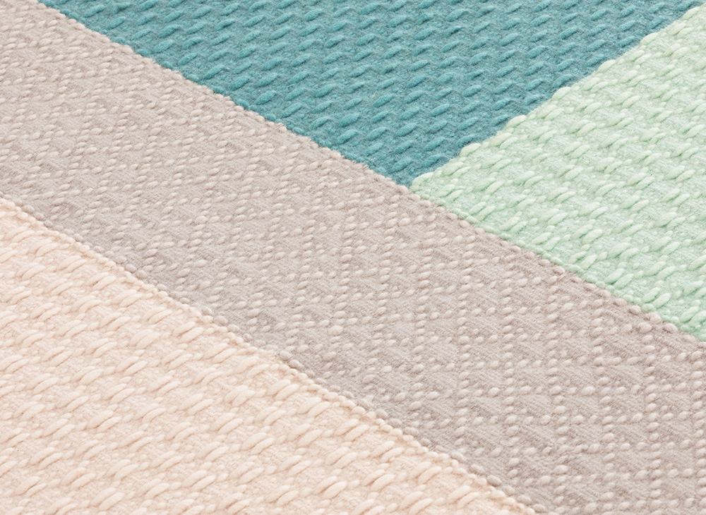 Detailaufnahme des Weave Rug Teppichs Meeting Point Gan mit geometrischem Muster in Beige, Grau, Türkis und Mint.