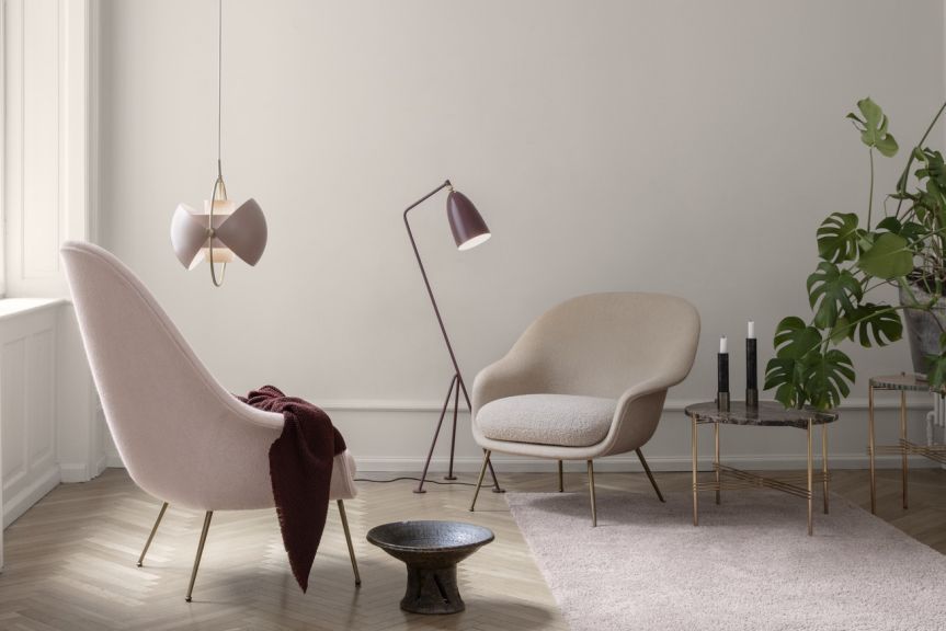 Gubi Multi-Lite Pendelleuchte in Rose Dust/Messing über modernem Wohnzimmer mit Designermöbeln.