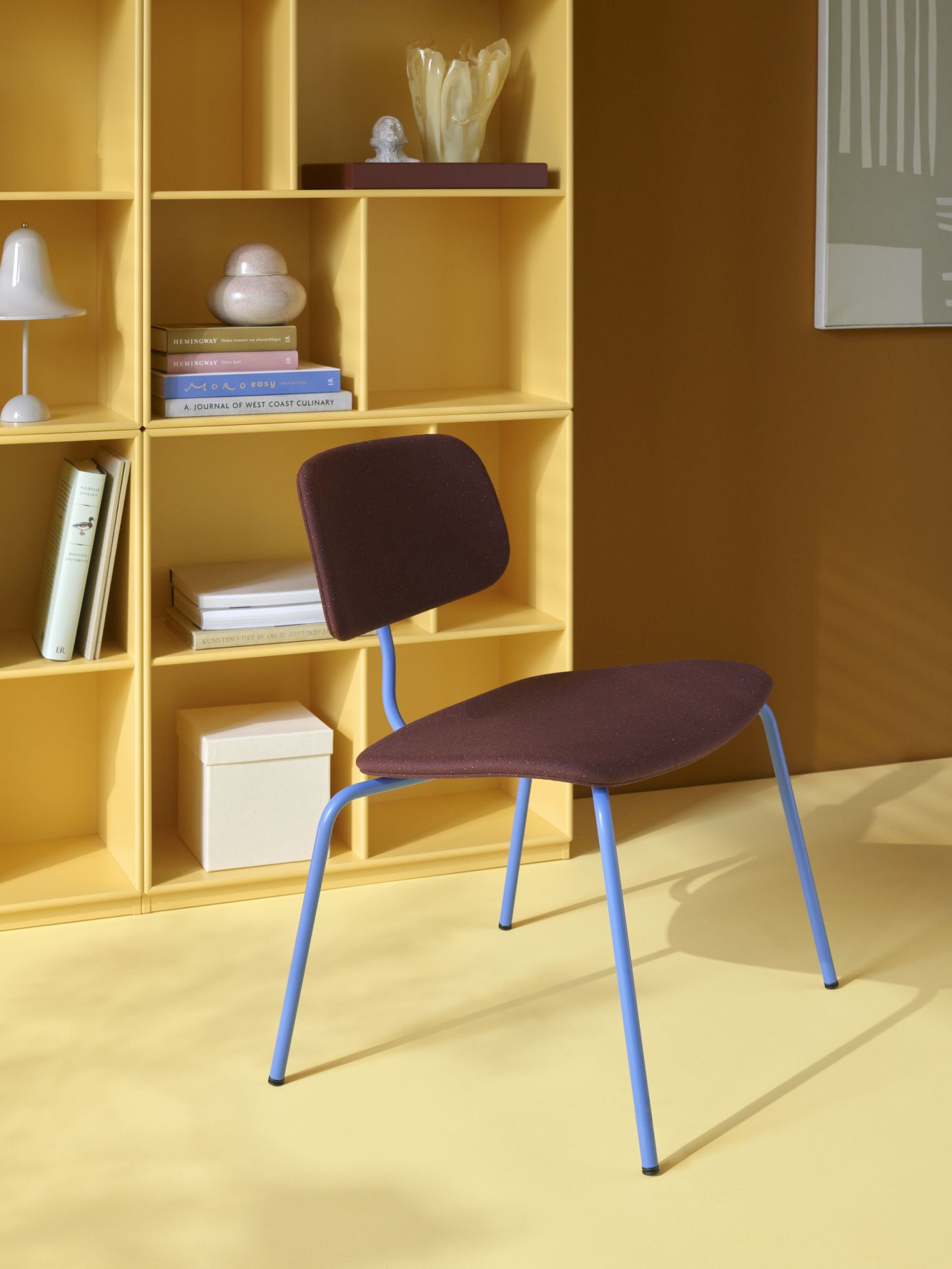 Gelbes Read Bücherregal mit braunem Stuhl und blauen Beinen, modernes Möbeldesign für Wohnzimmer.