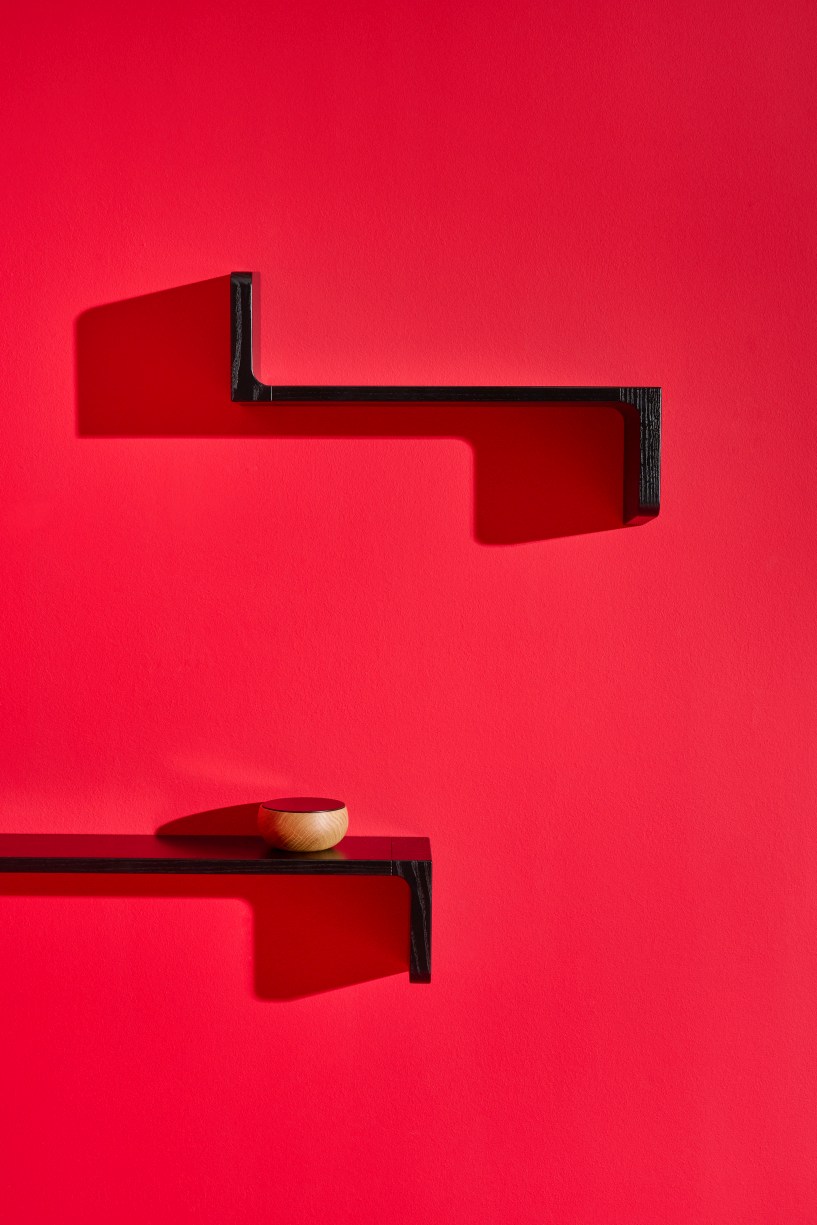 Schwarze Ulna Wandregale von Schönbuch an roter Wand, eines mit kleiner Holzschale dekoriert.