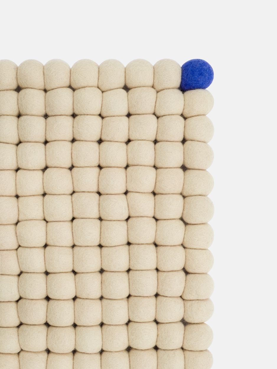 Detailansicht: Beige myfelt Filzteppich "Big One" (200x300cm) mit blauer Filzkugel. Rechteckiger Wollteppich aus Filzkugeln.