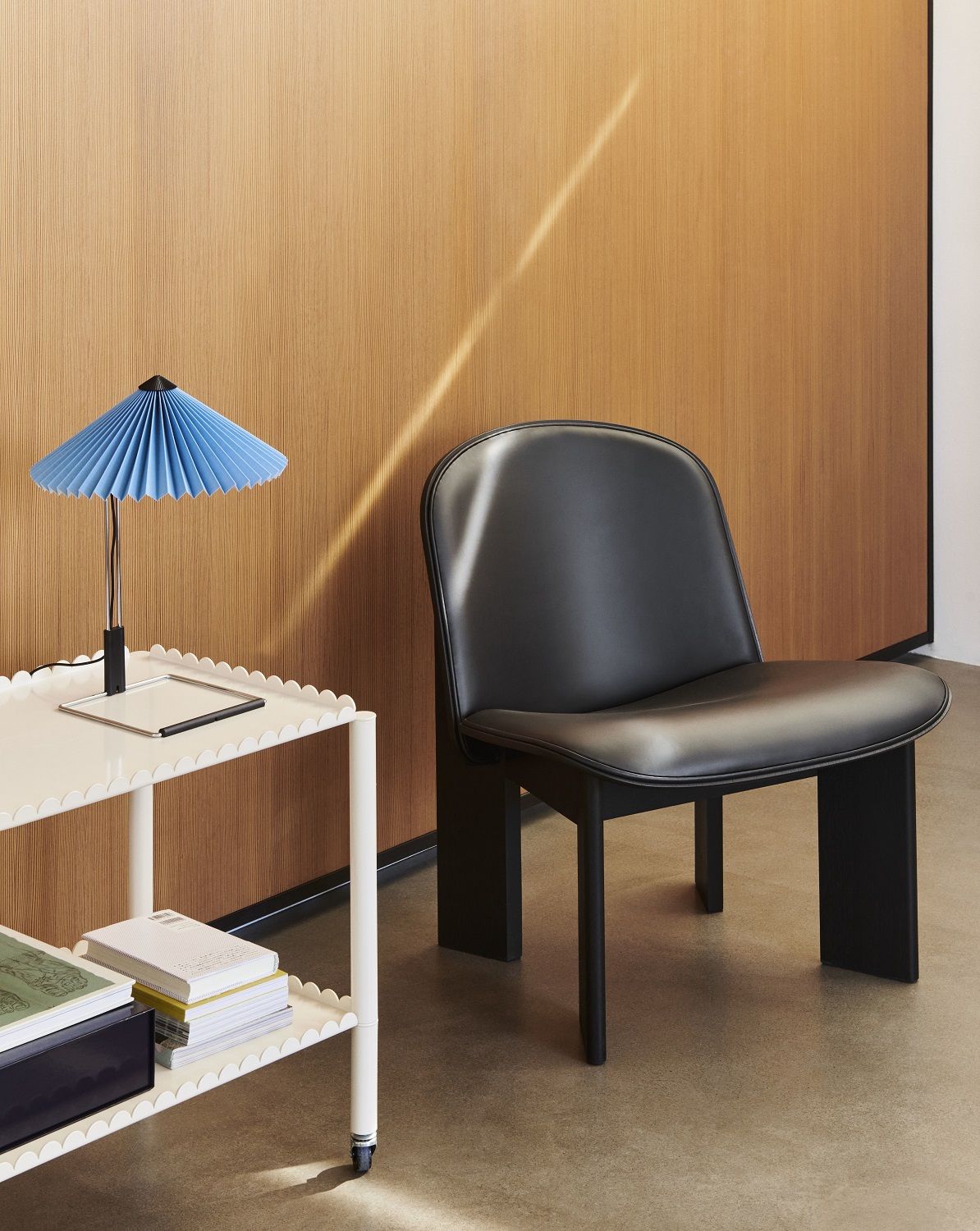 Schwarzer Chisel Lounge Chair Sessel von Hay, vollgepolstert, neben einem Beistelltisch und einer Lampe.