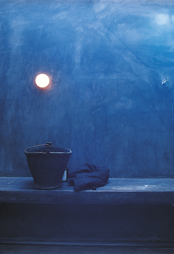 Mini Glo Ball Wandleuchte von Flos an blauer Wand, neben Eimer und Bademantel.