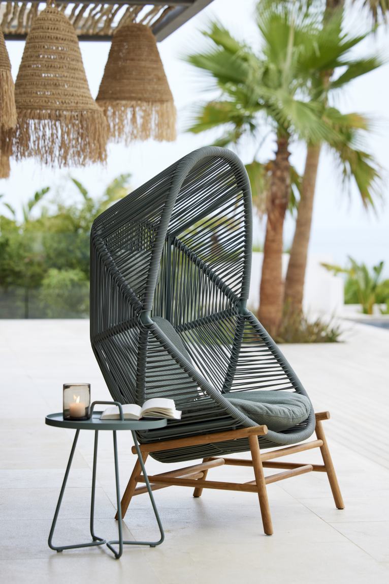 Cane-Line Hive Sessel für den Outdoor-Bereich, graues Flechtwerk und Holzelemente, mit Beistelltisch.