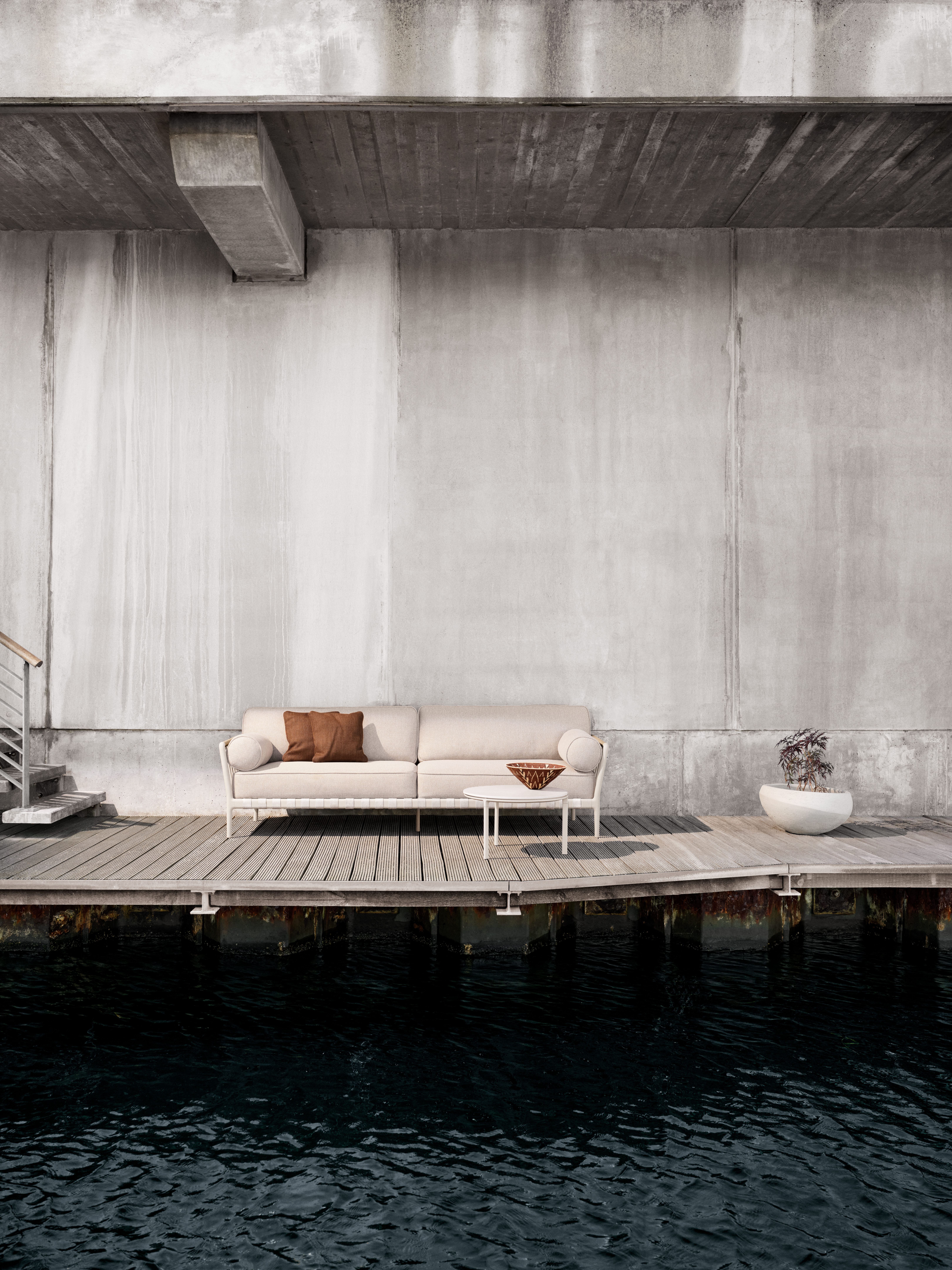 Vipp Open-Air 3-Sitzer Outdoor Sofa auf Holzterrasse am Wasser, minimalistisches Design.