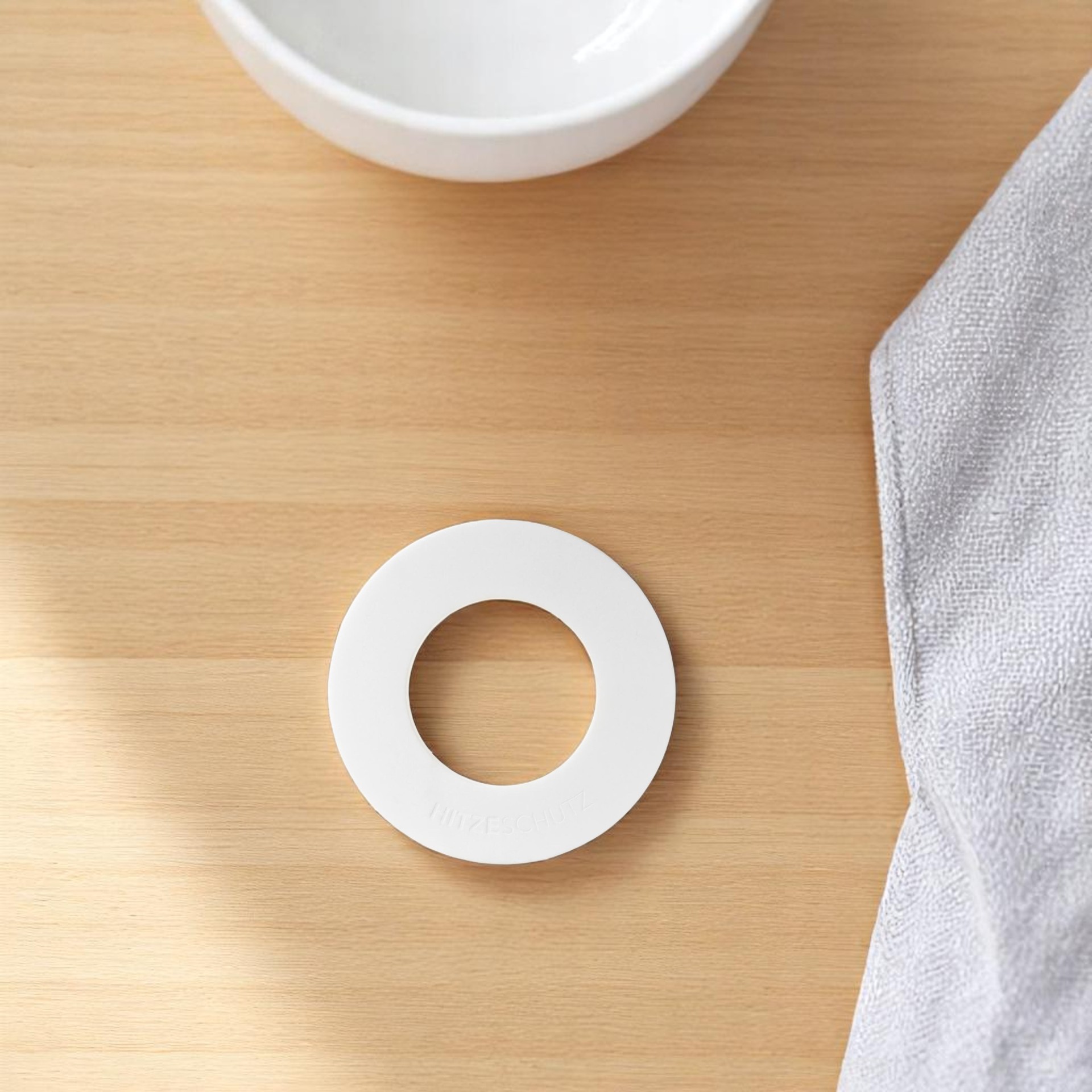 Weißer Topfuntersetzer mit Loch in der Mitte als Hitzeschutz für Töpfe und Pfannen.