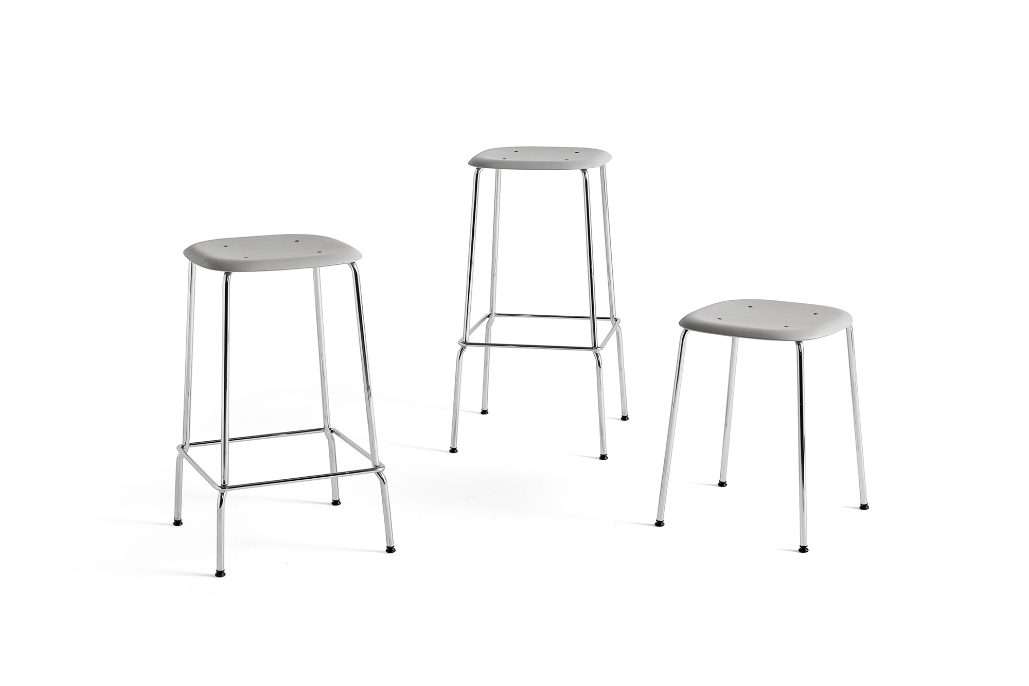 Drei graue Hay Soft Edge 85 Hocker mit Chromgestell auf weißem Hintergrund.