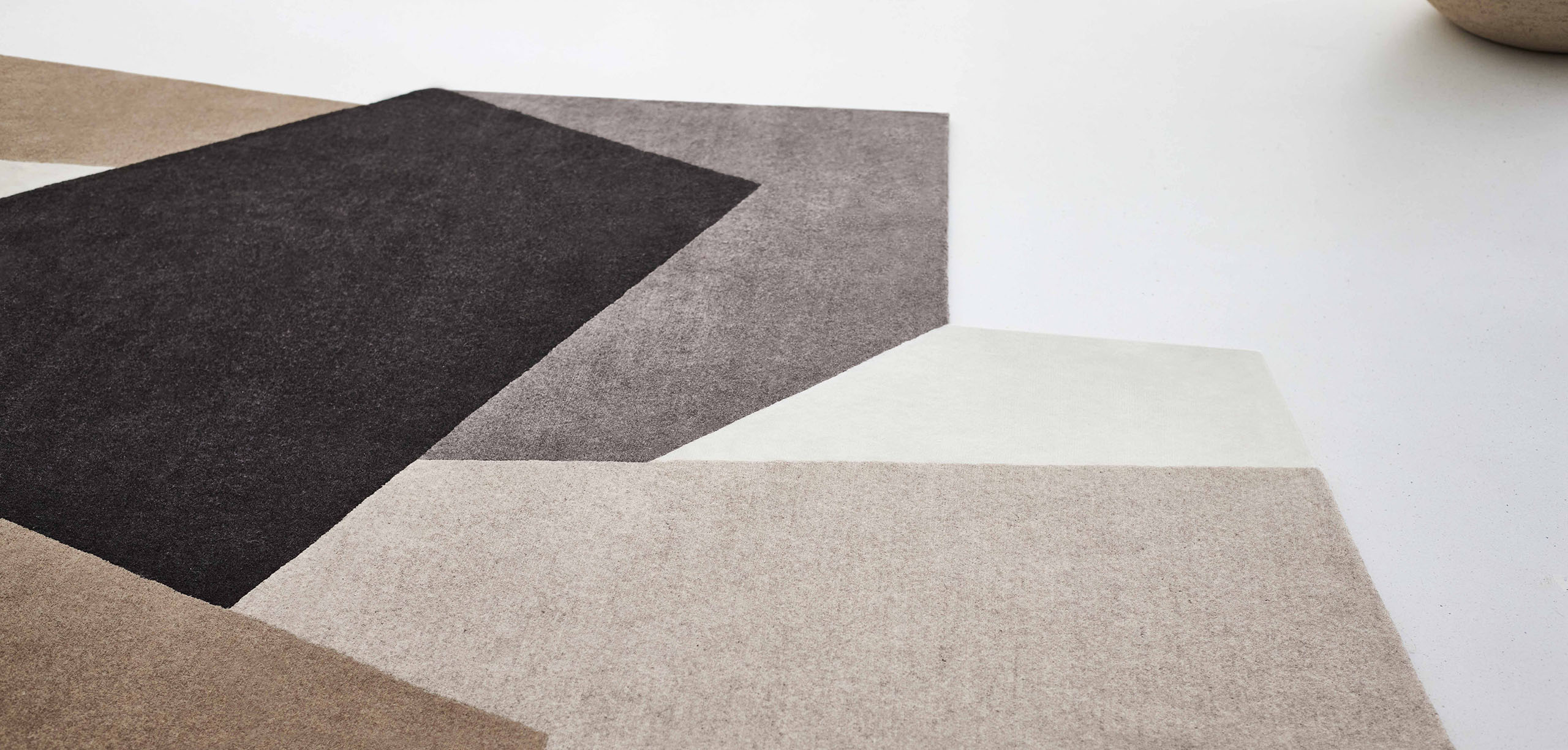 Detailaufnahme des Loko Rug Teppichs in Naturtönen mit geometrischen Mustern. Hochwertiger Wollteppich.