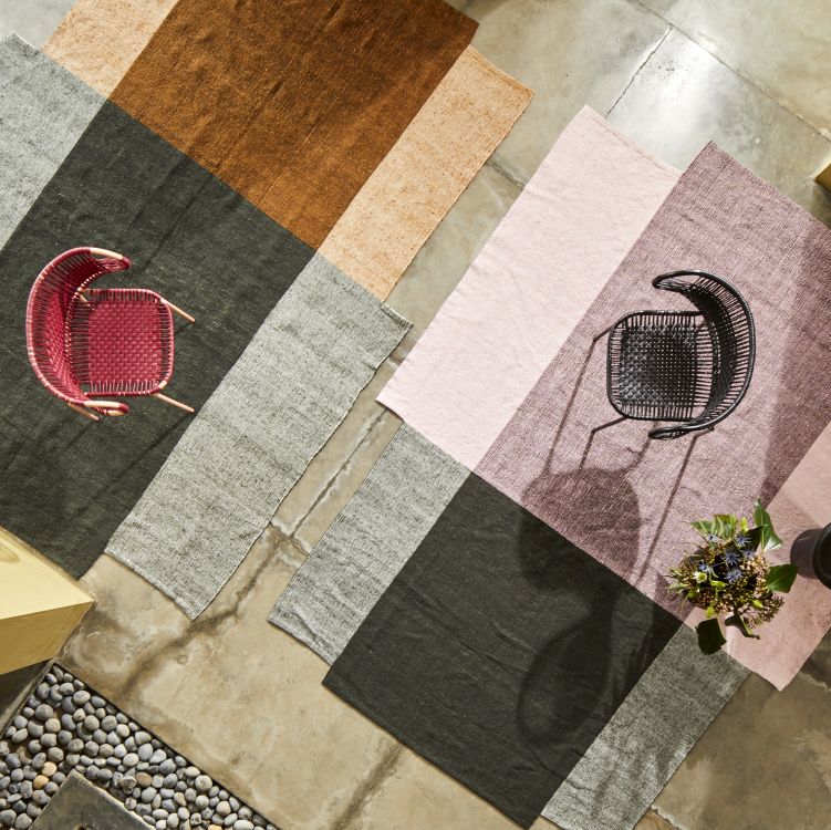 Ansicht von oben: Mehrfarbige Nobsa Teppiche mit Stühlen auf einem Betonboden.