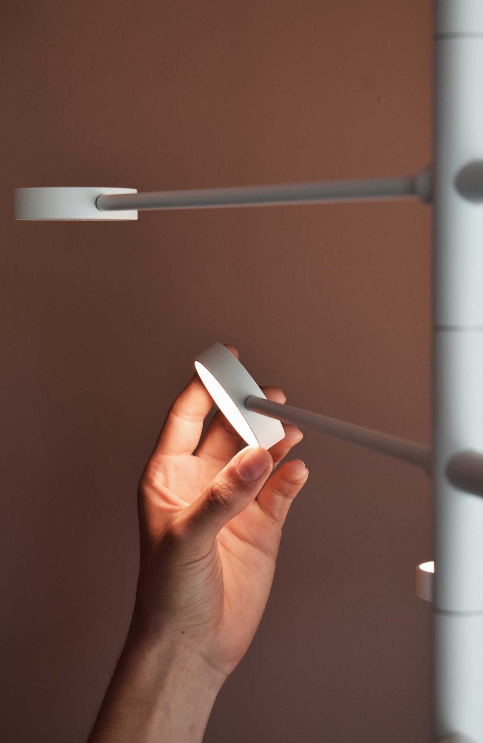 Hand hält KINGPIN Pendelleuchte Japth, modernes Design, minimalistische Hängelampe, warmes Licht.