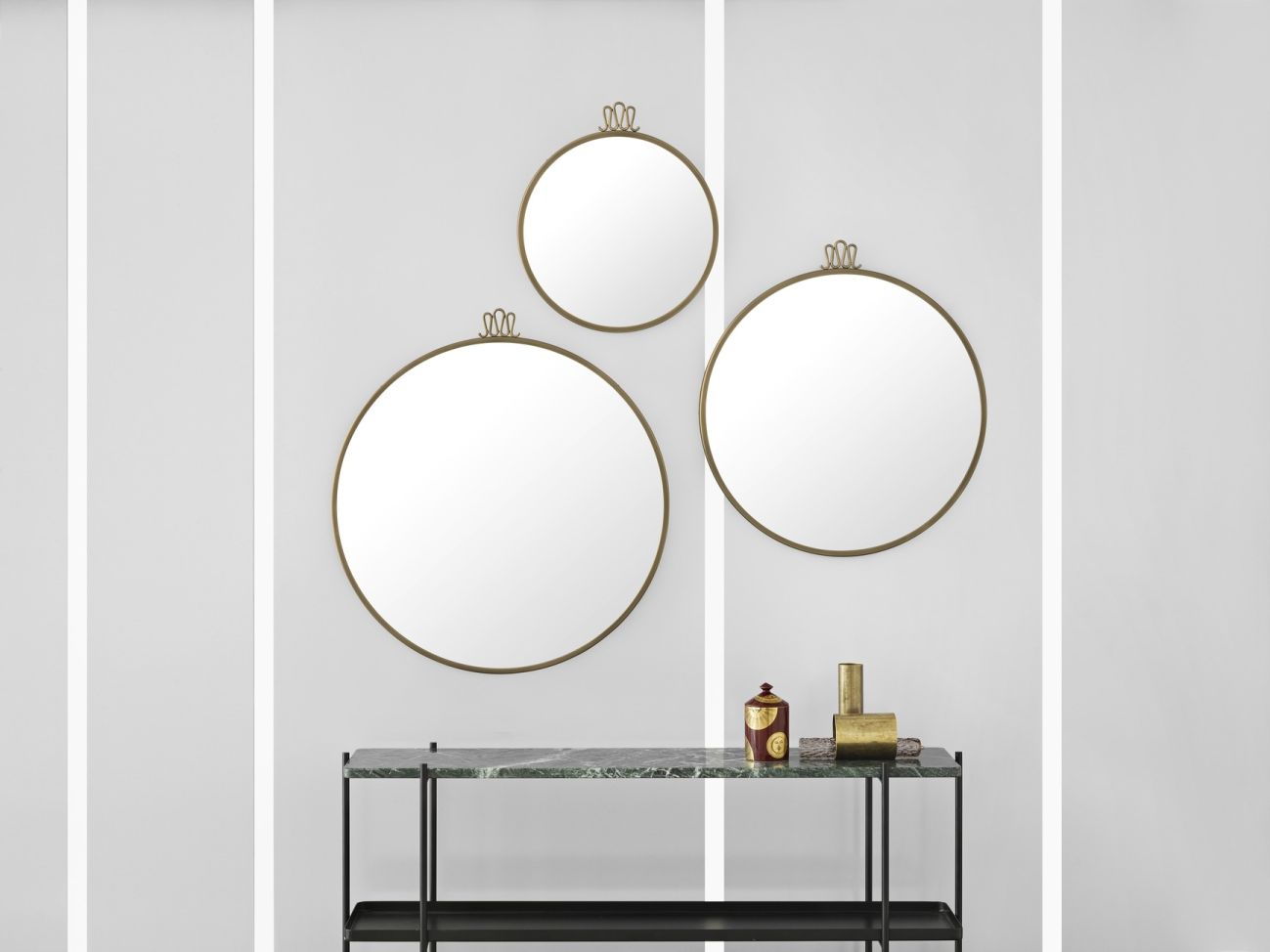 TS Konsole mit Tablett von Gubi und drei runden Wandspiegeln in Gold vor weißer Wand.