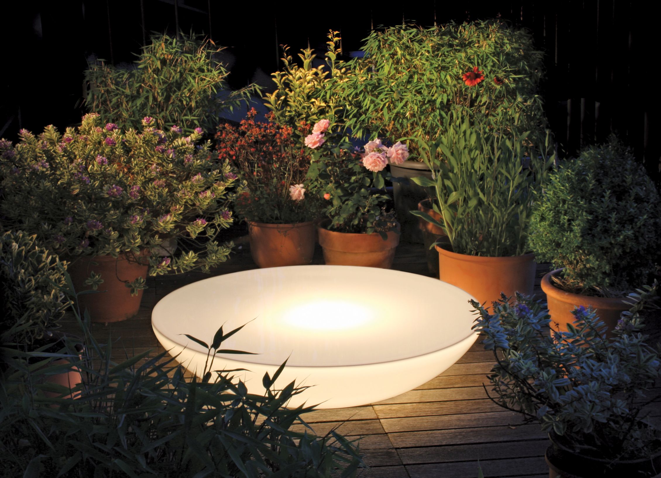 Moree Lounge Beistelltisch mit LED Beleuchtung im Garten zwischen Pflanzen.