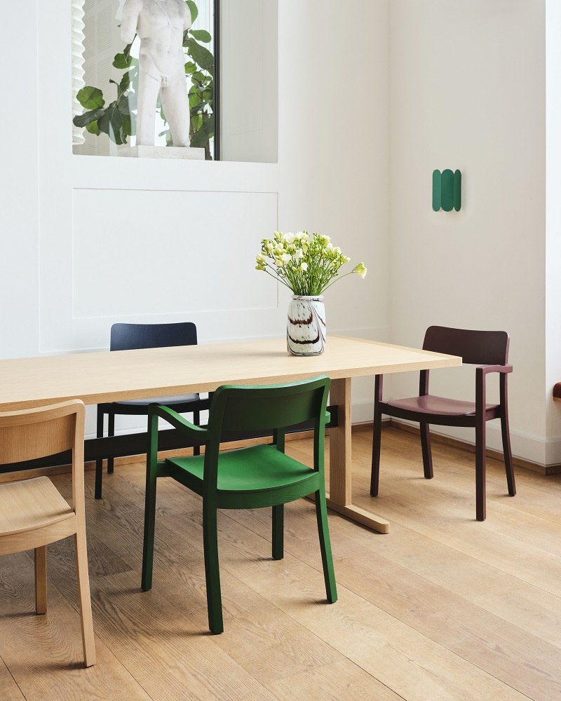 Esszimmer mit Esstisch und mehreren Hay Armlehnstühlen, darunter ein schwarzer Pastis Stuhl.