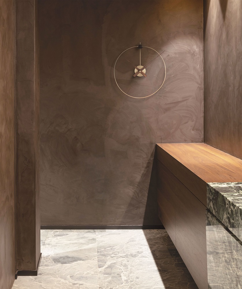 Micro Anda Clock Wanduhr: Runde, minimalistische Wanduhr von Nomon mit goldenem Rahmen und Holzzeigern.