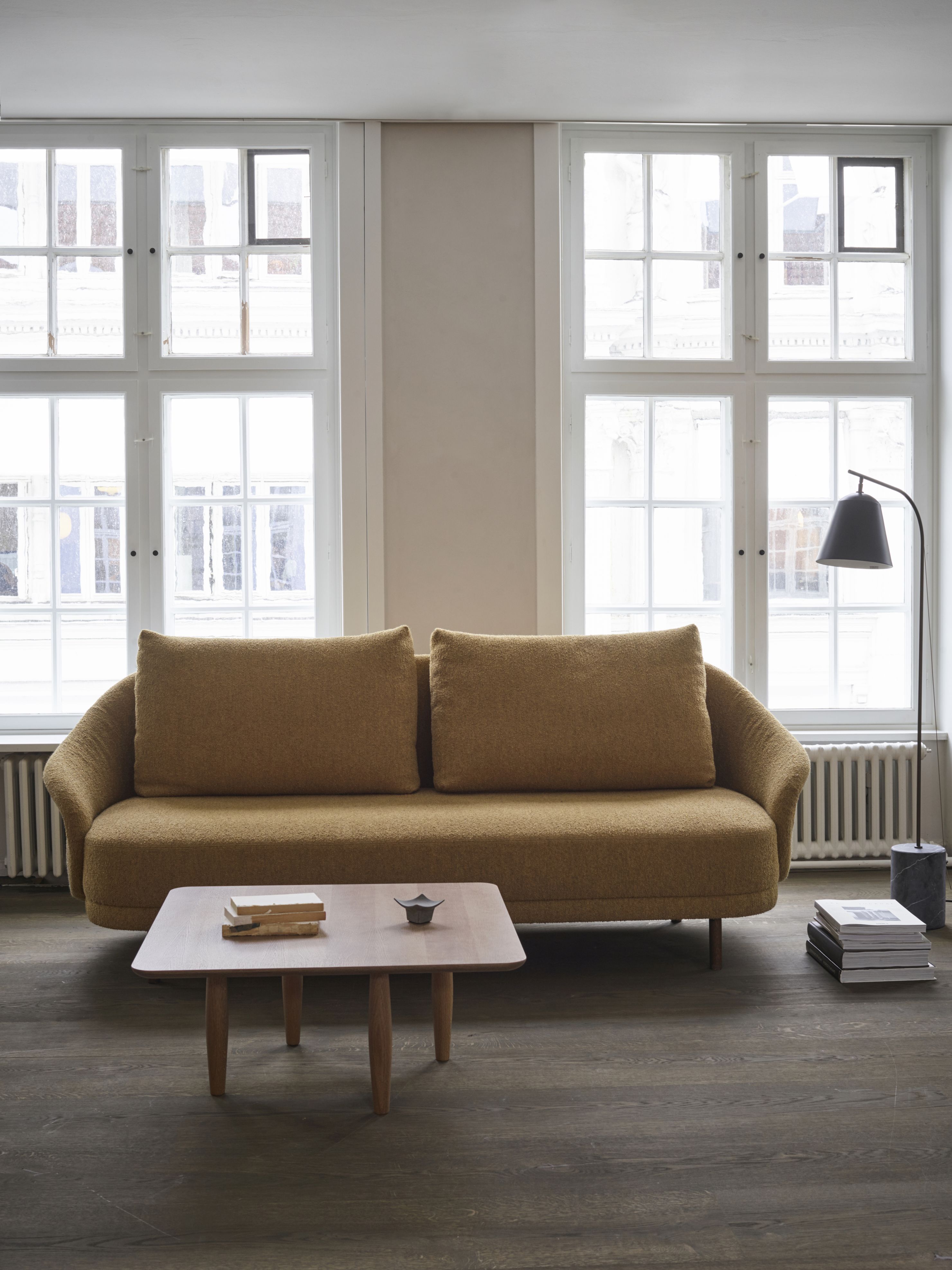 Oku Couchtisch aus Eiche dunkel geräuchert von Norr11 vor Sofa und Fenstern.