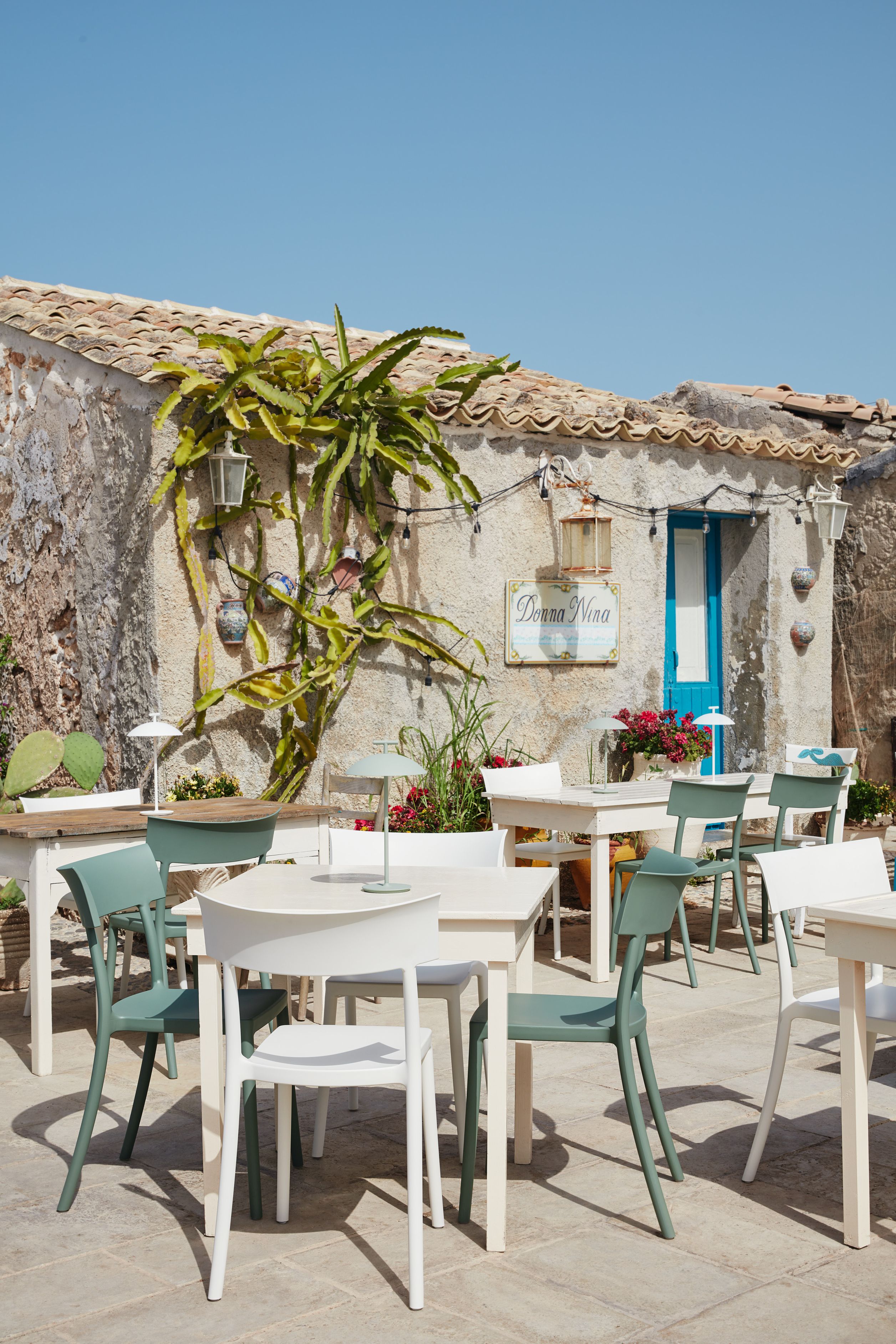 Außenbereich mit Tischen und Stühlen, darunter ein schwarzer Kartell Stuhl (Catwalk Modell).