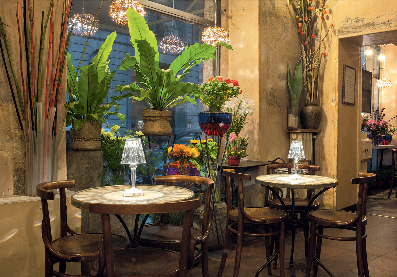 Big Battery Tischleuchte von Kartell in Cola-Farbe auf einem Tisch in einem Café.