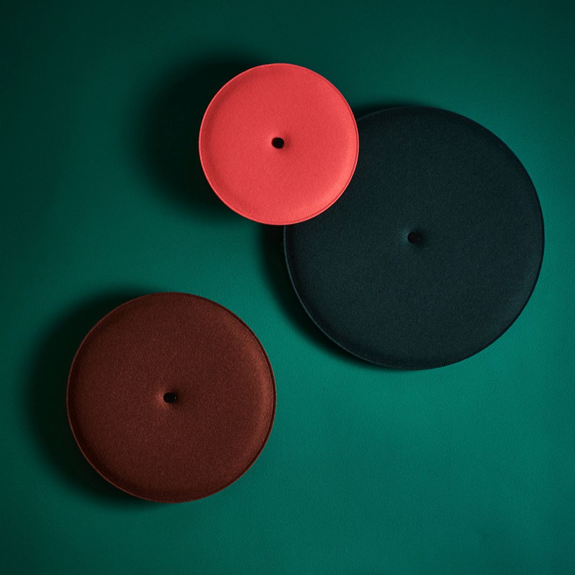 Drei farbige Hey Sign Wandelemente Spot aus Filz an einer grünen Wand.