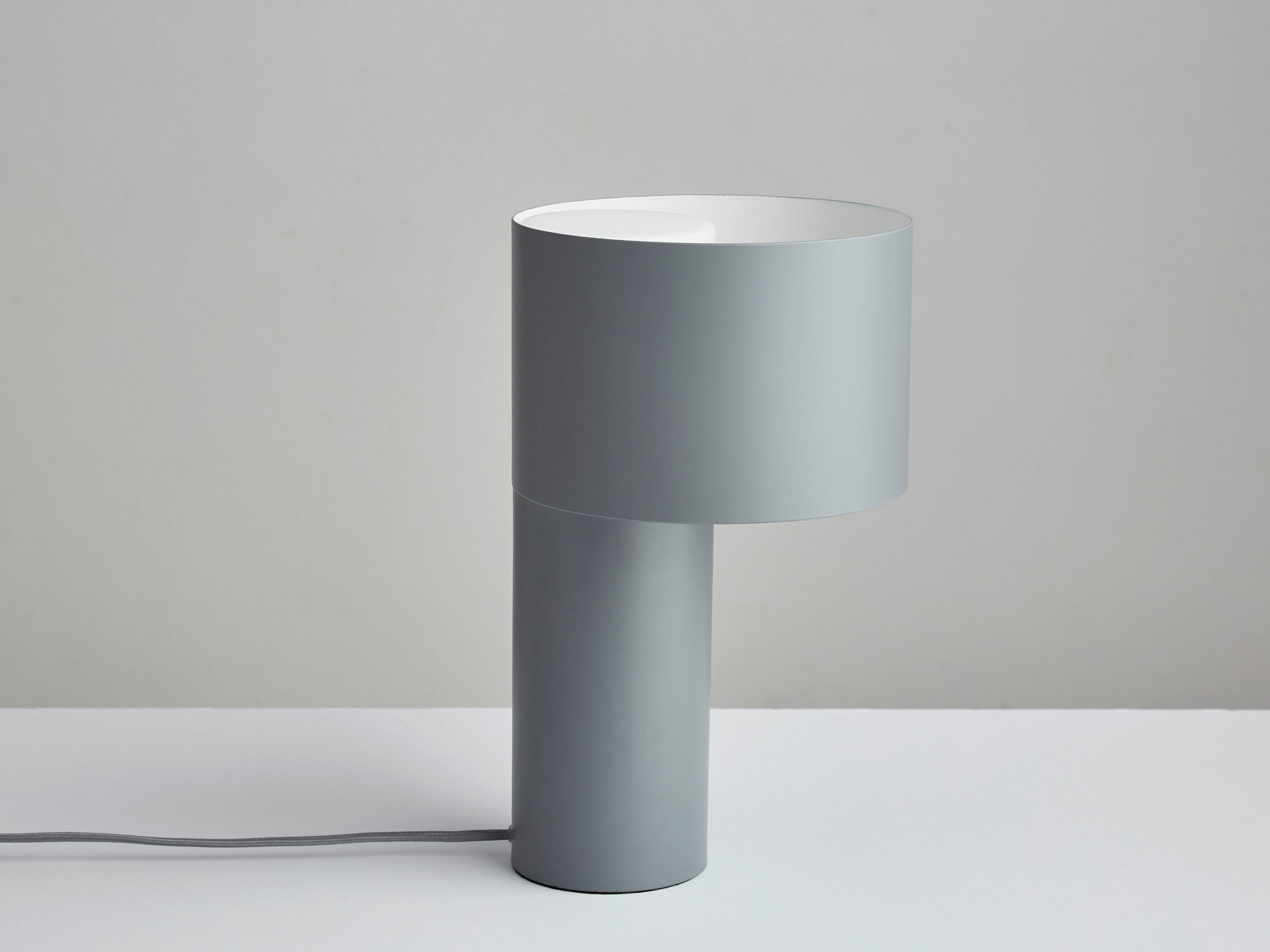 Nahaufnahme der grauen Tangent Table Lamp Tischleuchte von Woud mit zylindrischem Lampenschirm.
