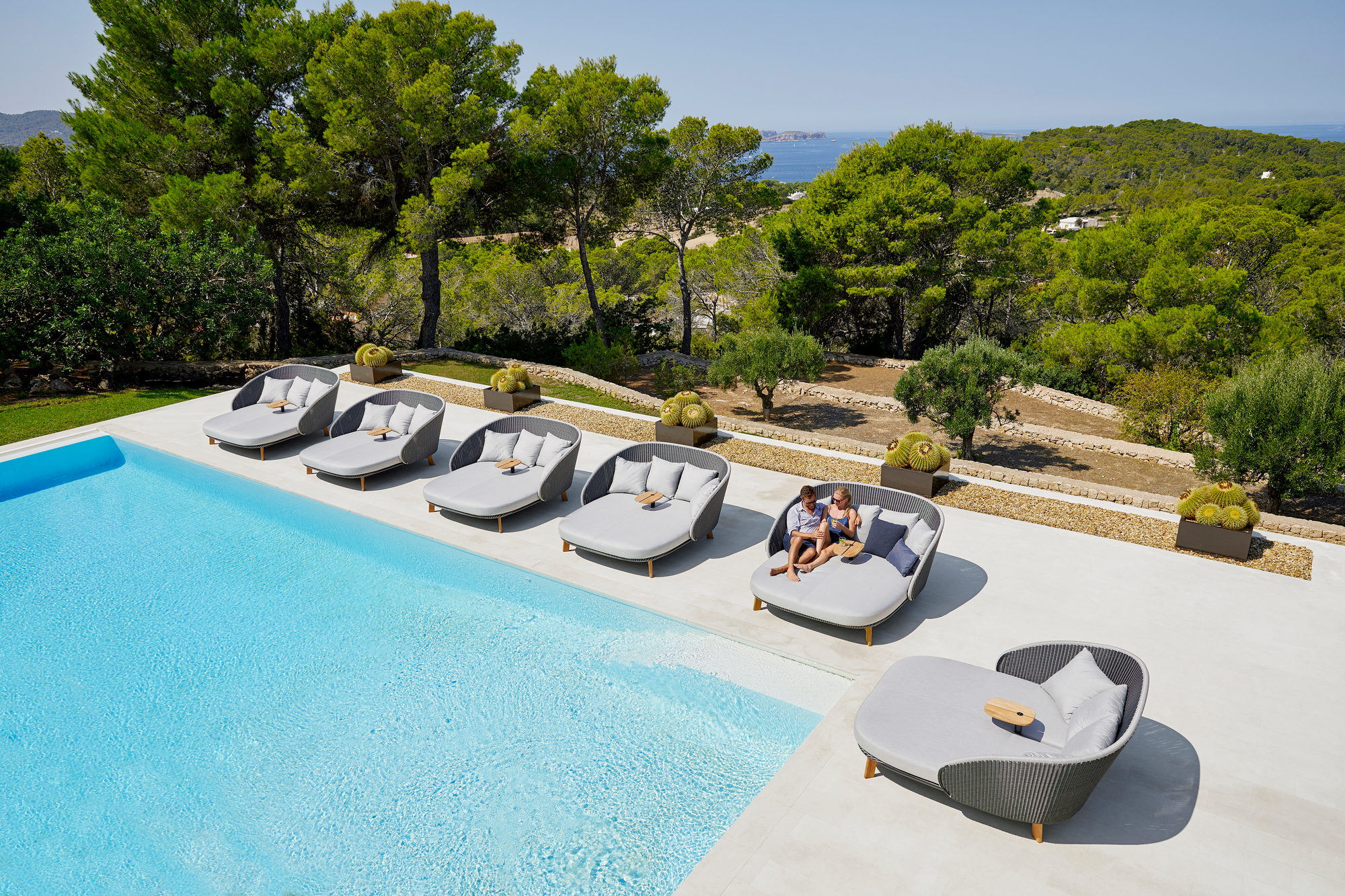 Peacock Outdoor Liegen von Cane-Line am Pool mit Tisch und Kissen, moderne Gartenmöbel.