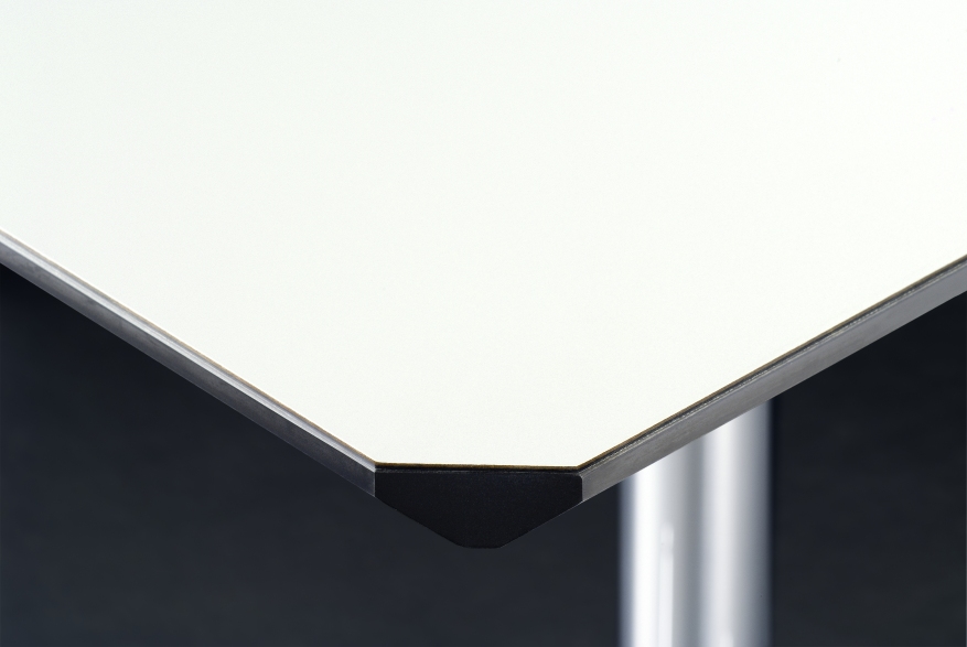 Detailaufnahme: USM Haller Kitos Tischplatte in Weiß mit schwarzer Kante und verchromtem Tischbein.