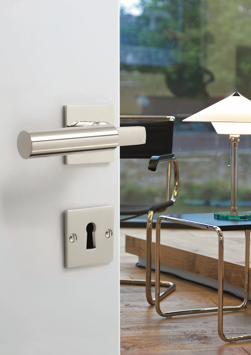 Walter Gropius Türdrücker Tecnolumen aus satiniertem Edelstahl, Detailaufnahme an weißer Tür mit Bauhaus-Interieur.