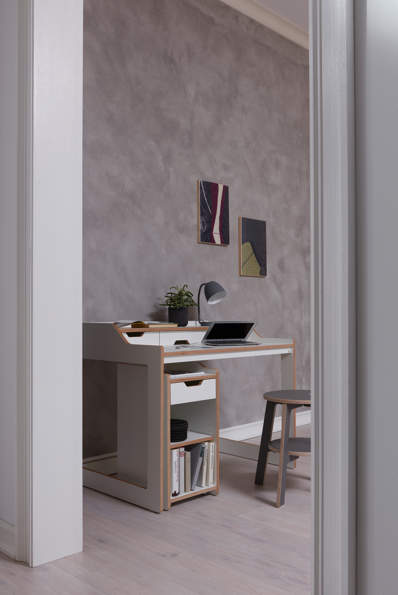 Moderner Rollcontainer Schreibtisch von Müller Möbelwerkstätten mit Laptop, Lampe und Hocker im minimalistischen Design.