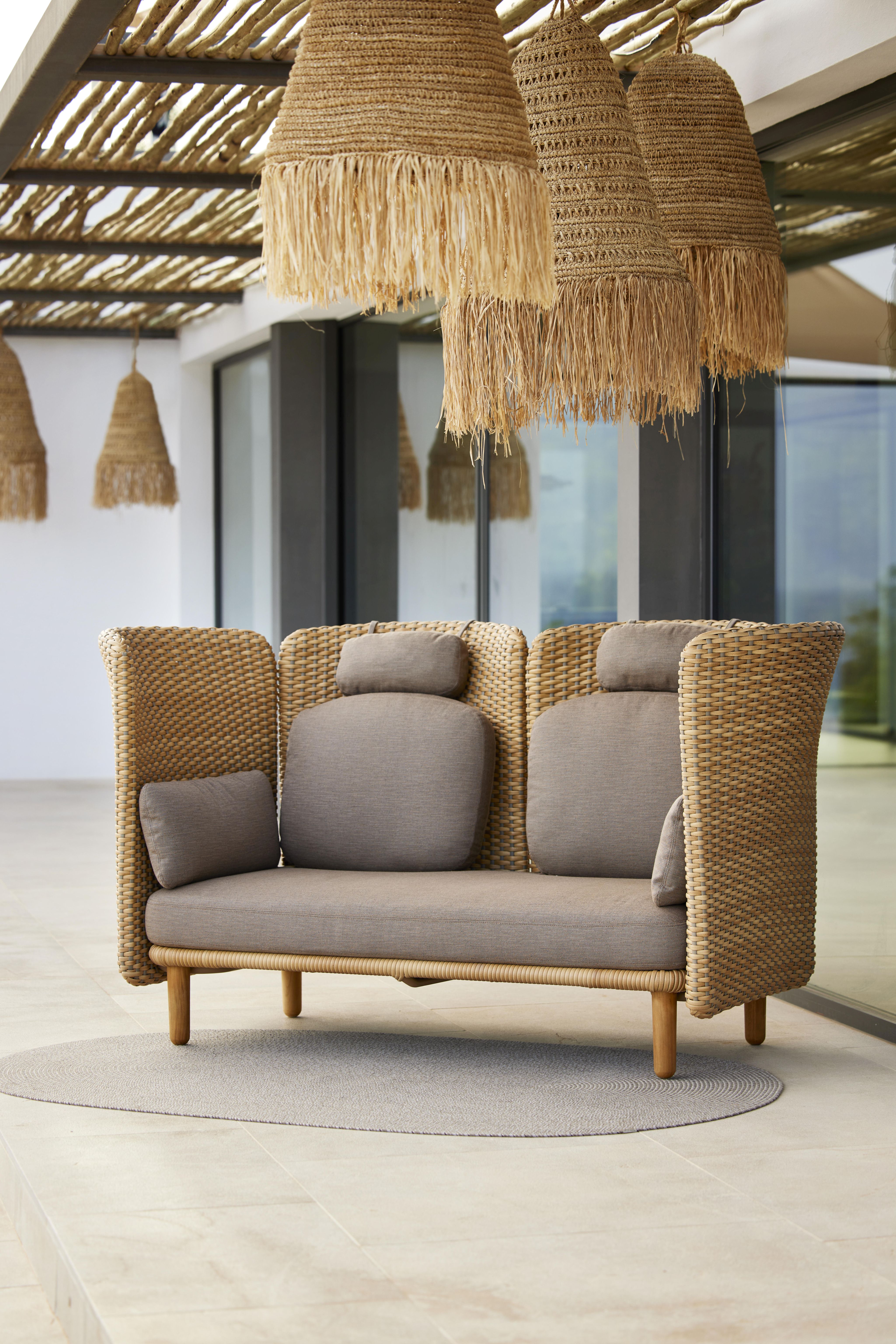 Arch Outdoor Sofa von Cane-Line mit Arm- und Rückenlehne aus Rattan, graue Kissen.