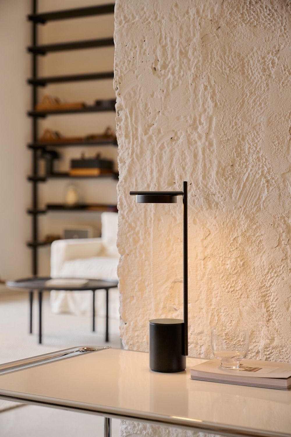 Igram Akku Tischleuchte von Grupa in Messingoptik auf einem weißen Tisch.