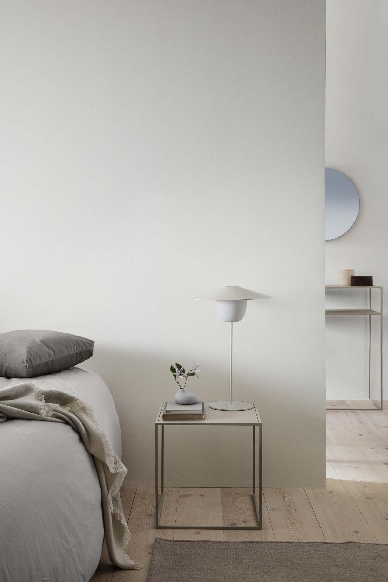 Ani Mobile LED Tischleuchte Warmgrau von Blomus auf Nachttisch neben Bett. Moderne, tragbare Lampe.