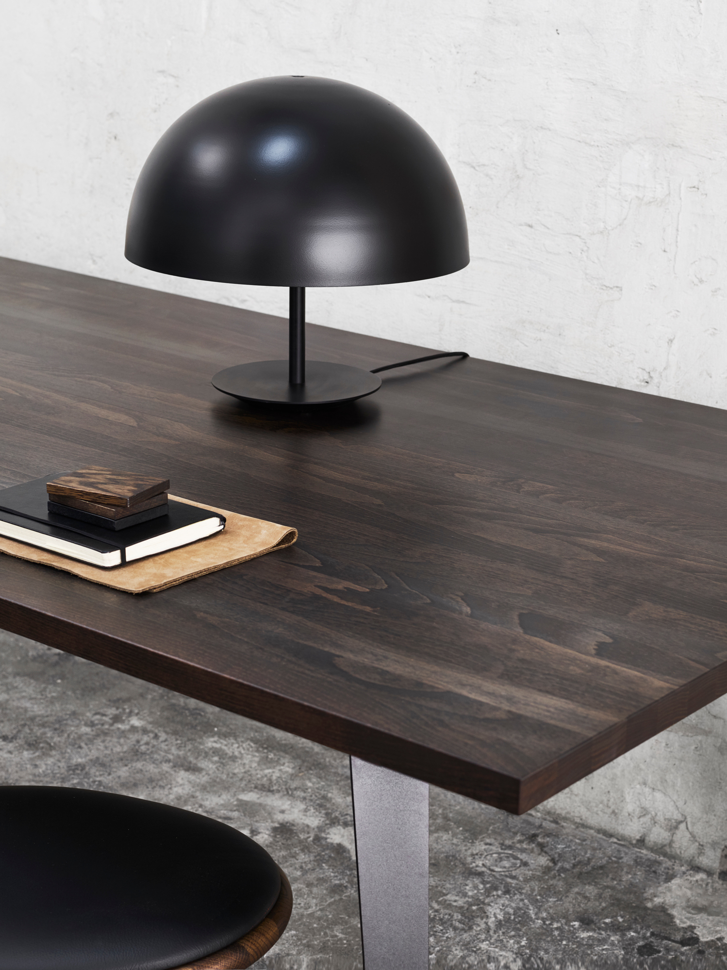 Schwarze Baby Dome Lampe von Mater auf dunklem Holztisch mit Notizbüchern.