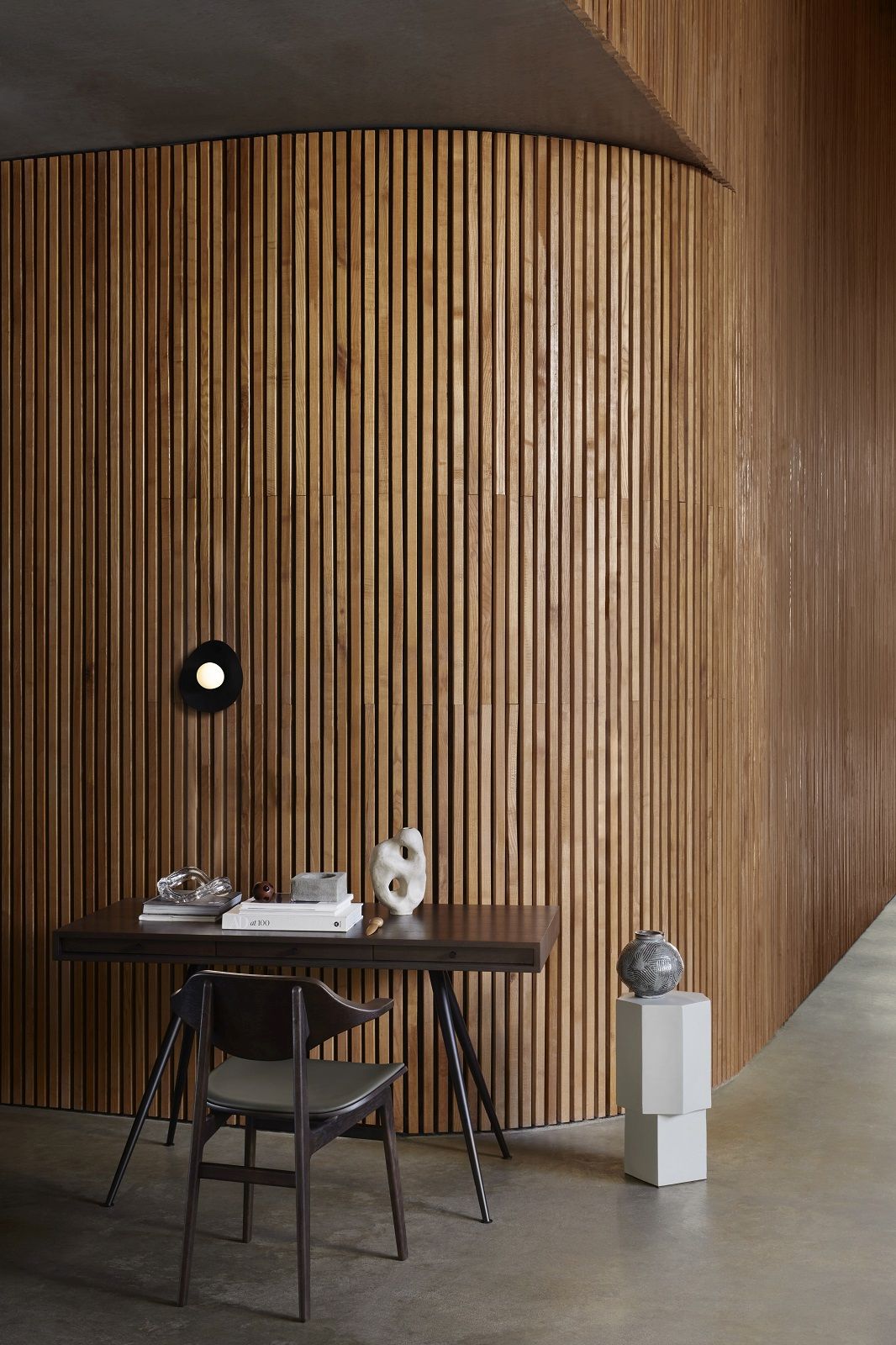 JFK Home Desk Schreibtisch von NORR11 vor einer Holzpaneelwand mit Dekoration und Stuhl.