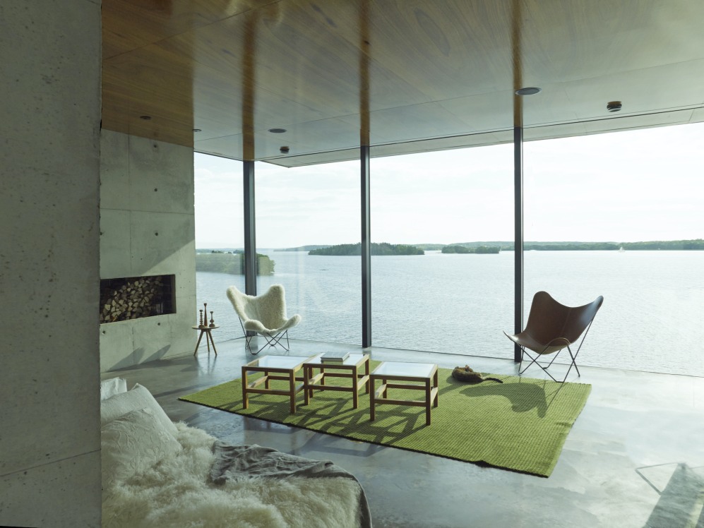 Wohnzimmer mit Iceland Mariposa Butterfly Sessel Schaffell in Grau und Leder vor Seeblick.