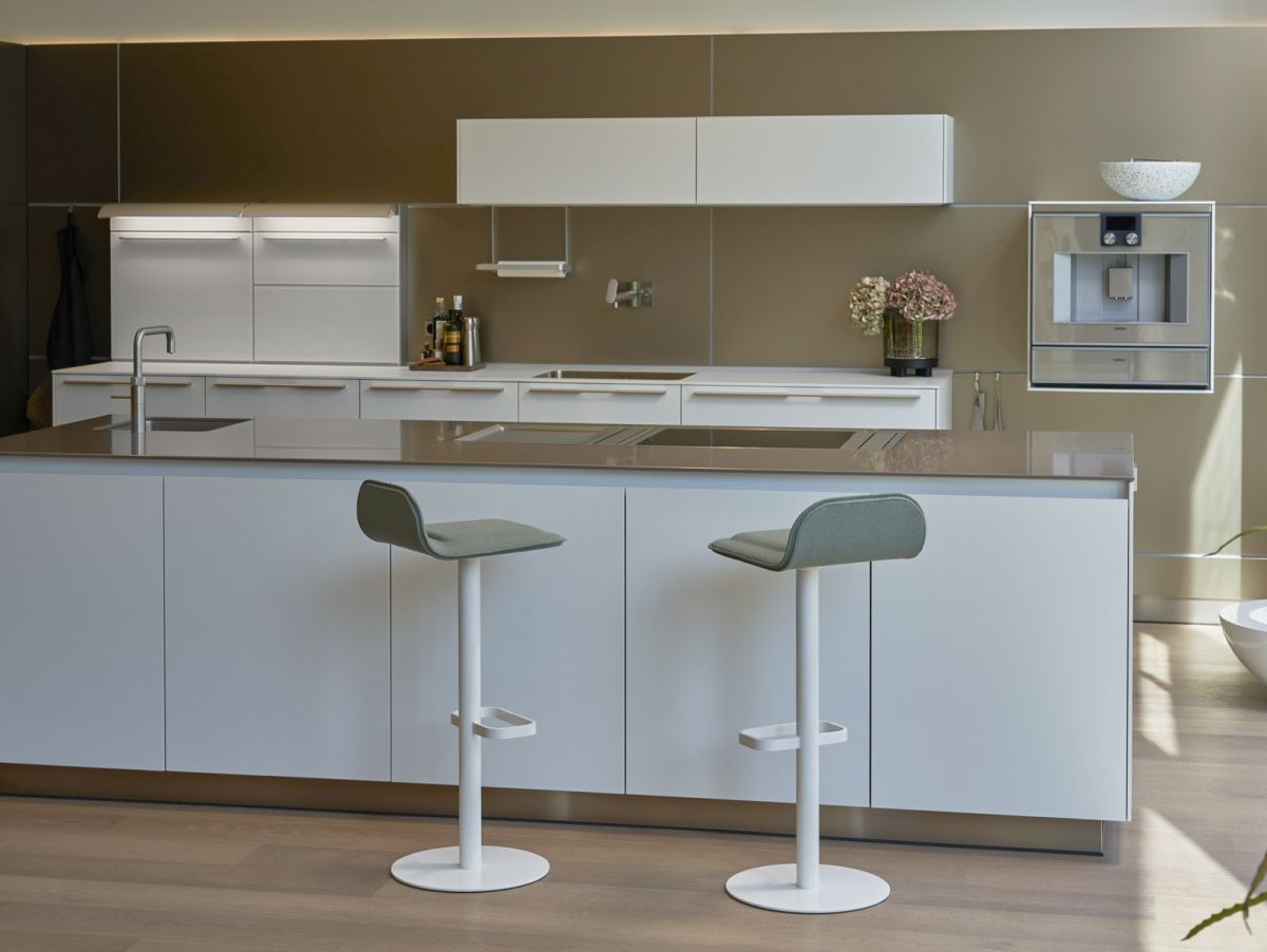 Moderner Dave Barhocker in Weiß mit salbeifarbenem Sitzpolster vor einer weißen Kücheninsel.