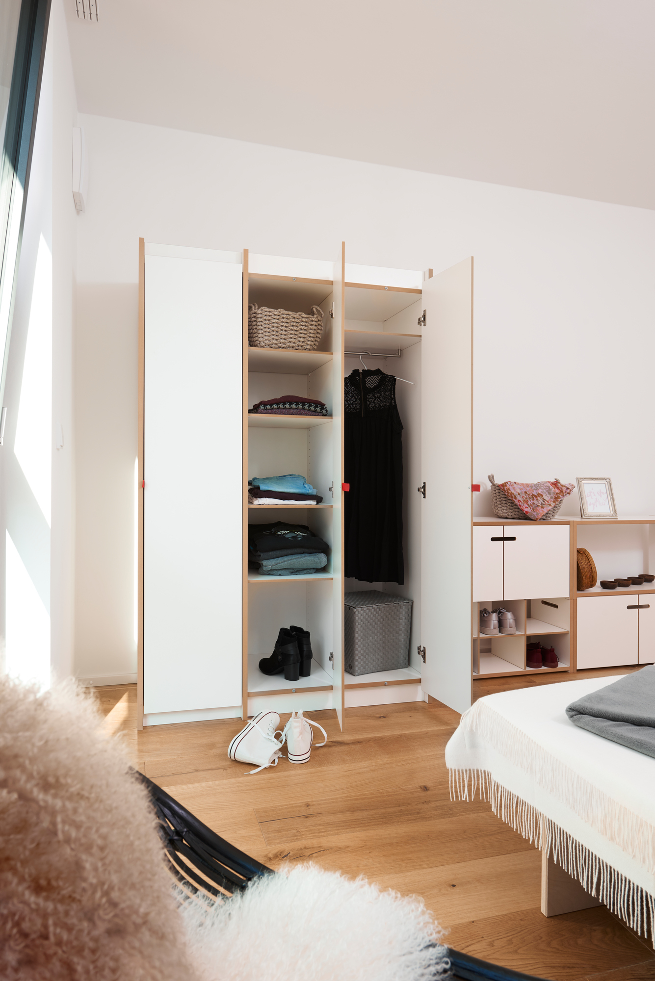 Offener, weißer Kleiderschrank mit Regalen und Kleiderstange, Teil des Tojo Schranksystems.