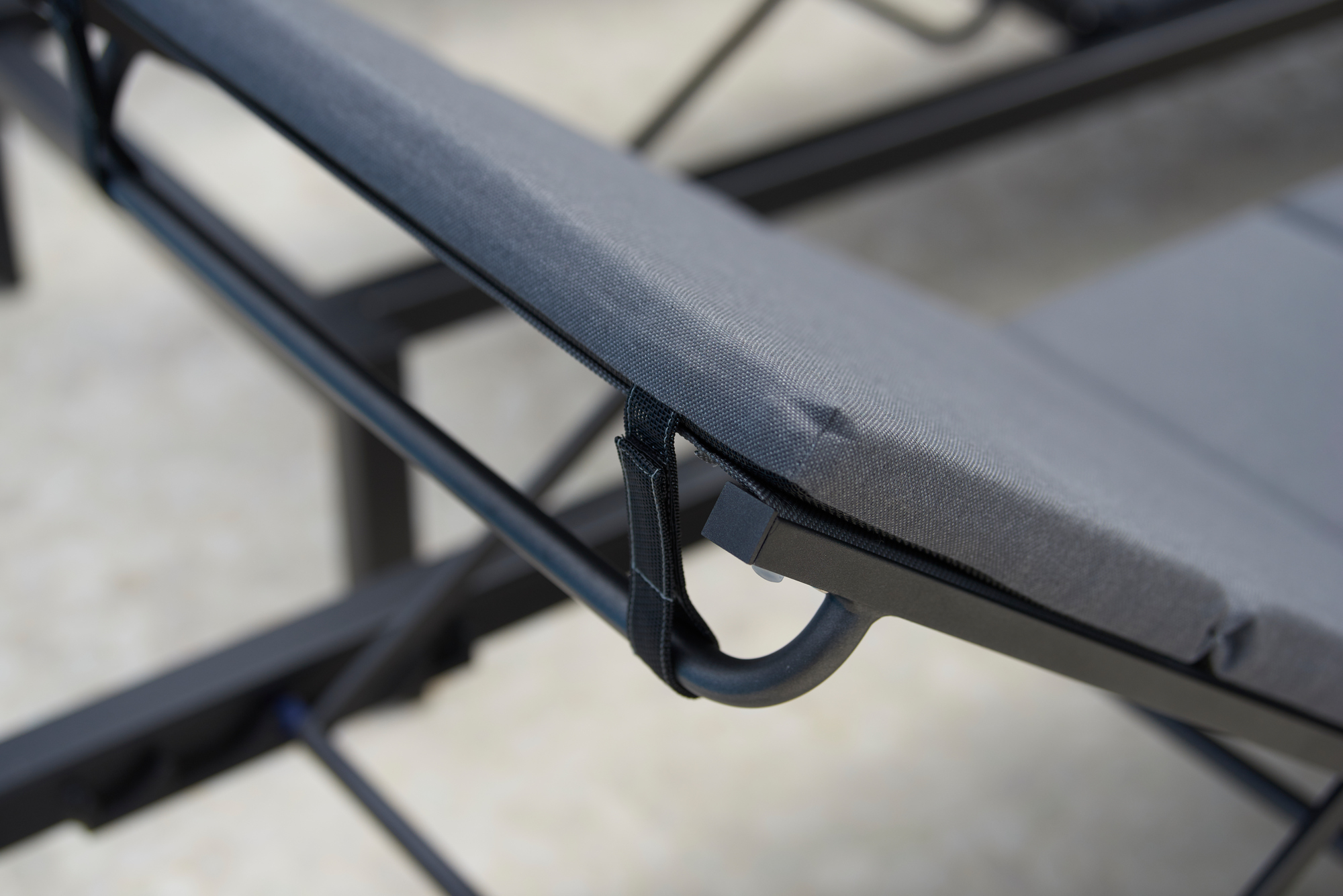 Detailaufnahme: Hellgraues Cane-Line Relax Outdoor Kissen für Sonnenliege, befestigt am schwarzen Gestell.