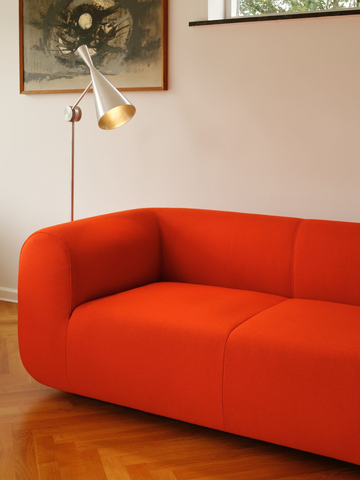 Nahaufnahme der Tom Dixon Unbeaten Stehleuchte neben einem modernen, orangefarbenen Sofa im Wohnzimmer.