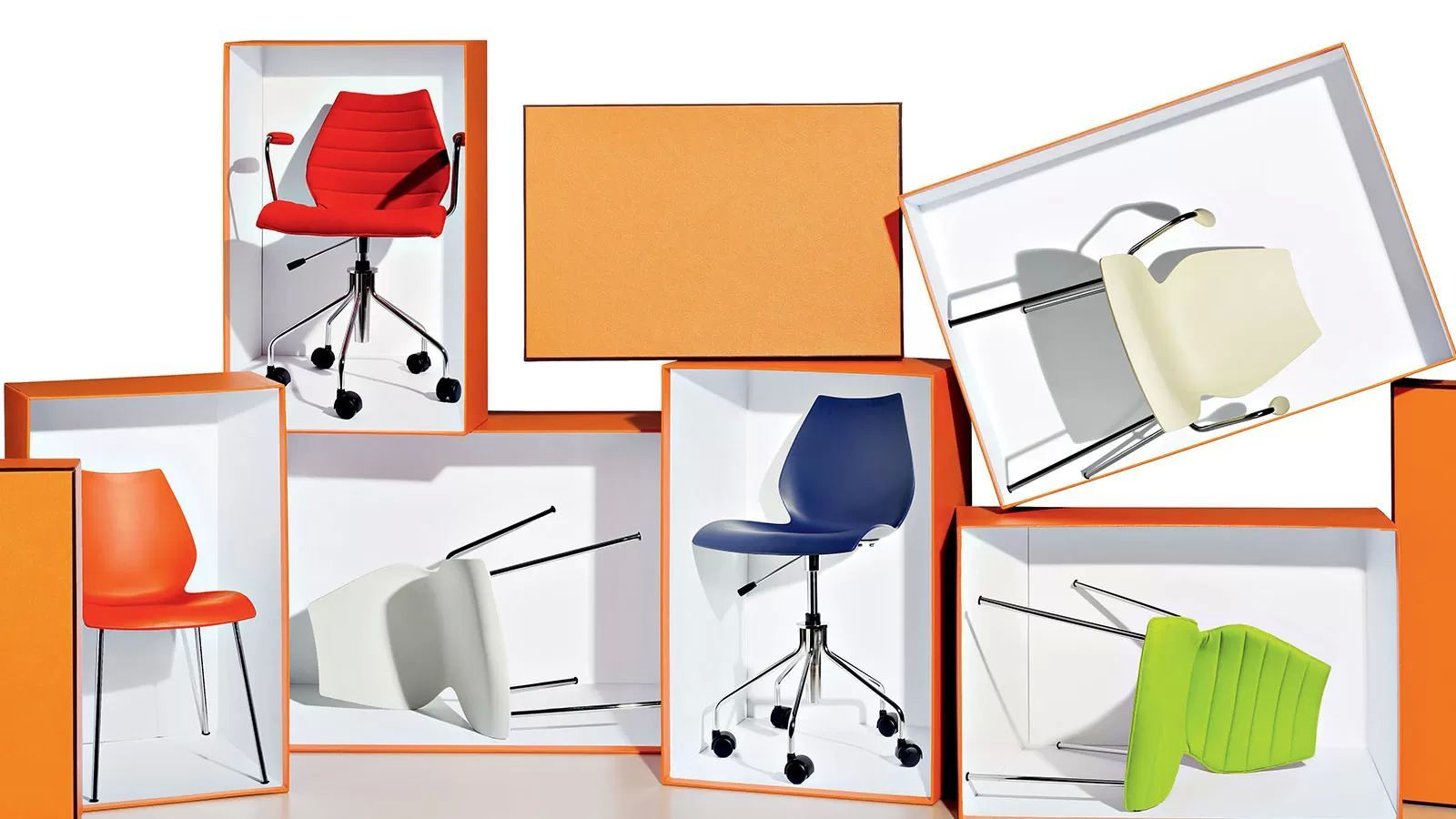 Mehrere Bürostühle in Kartons, darunter ein anthrazitfarbener Maui Stuhl mit Armlehne von Kartell.