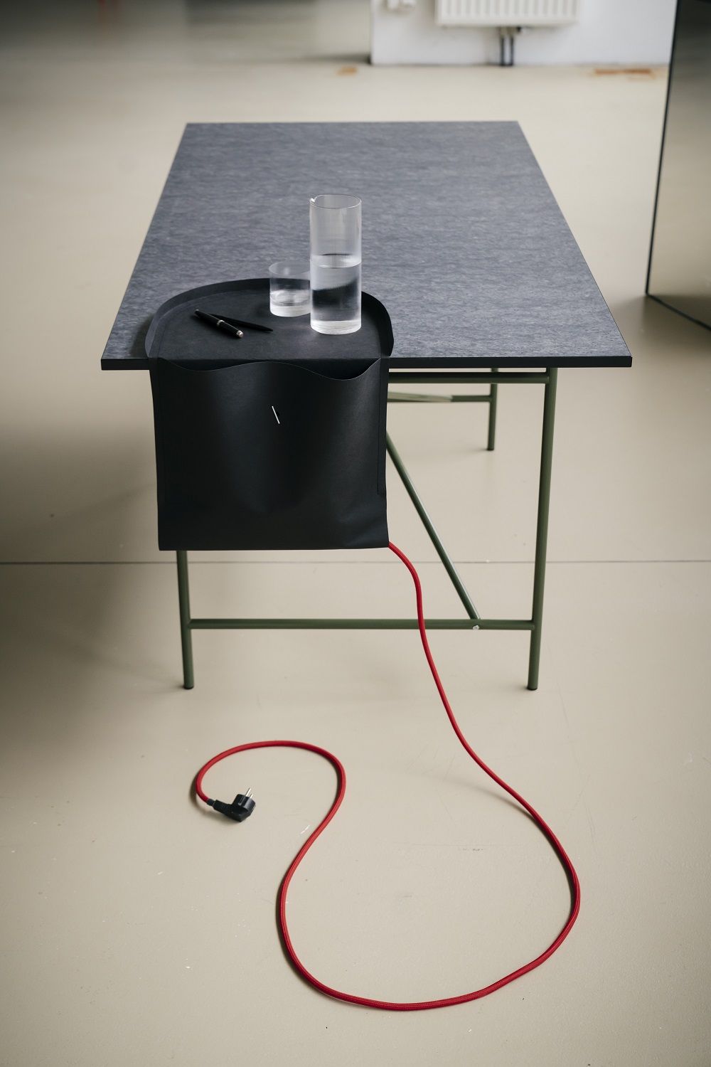 Salto Papiermöbel von Richard Lampert: Schreibtisch mit Organizer-Tasche und rotem Stromkabel. Büroorganisation und modernes Design.