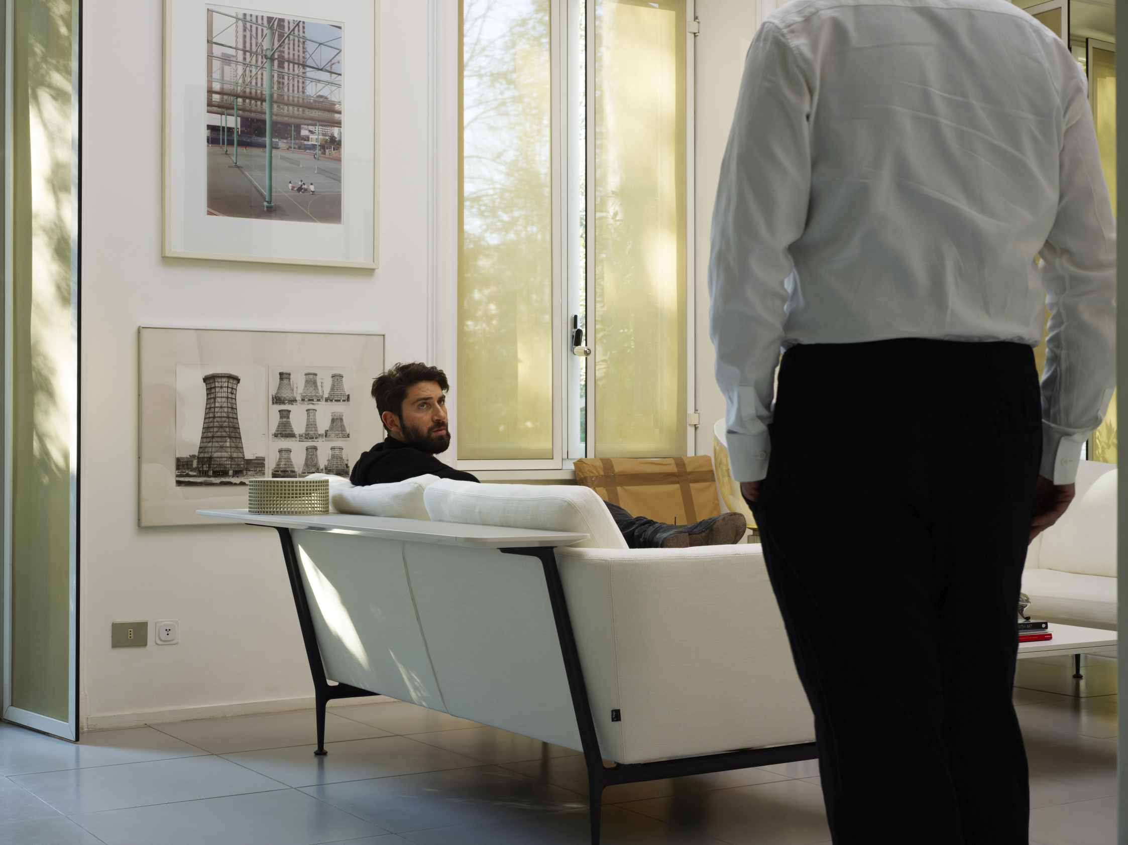 Mann liegt entspannt auf dem weißen Suita Sofa von Vitra im modernen Wohnzimmer.