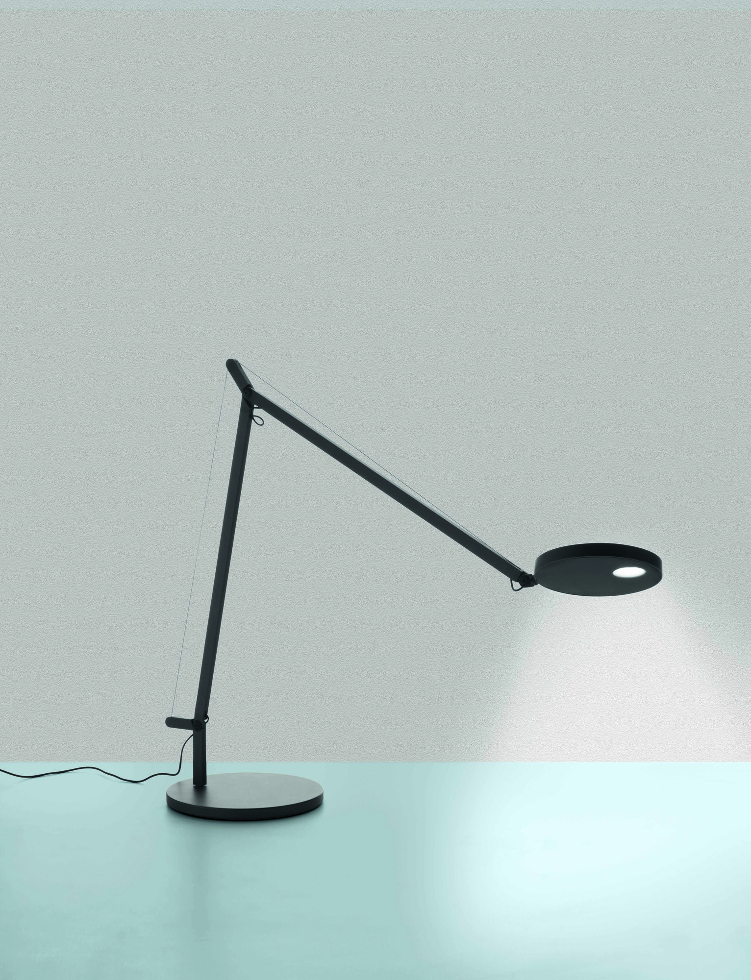 Demetra Tischleuchte von Artemide: Schwarze Schreibtischlampe mit verstellbarem Arm und rundem Leuchtenkopf.
