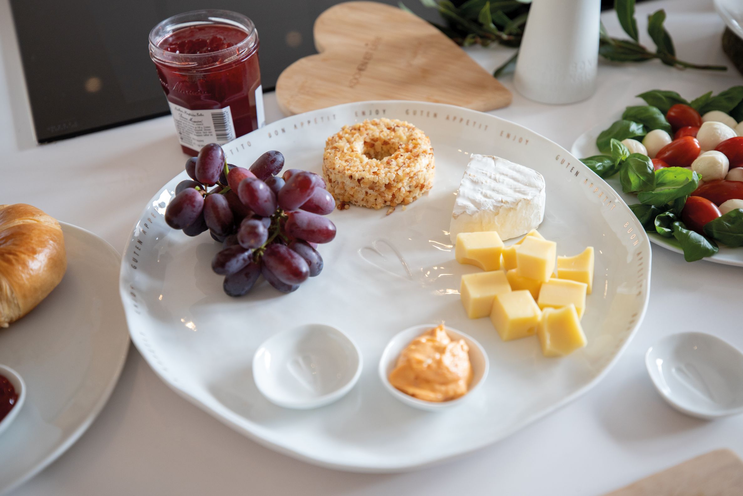 Guten Appetit Platte Räder: Servierplatte mit Käsewürfeln, Camembert, Trauben und Dips für Feinschmecker.