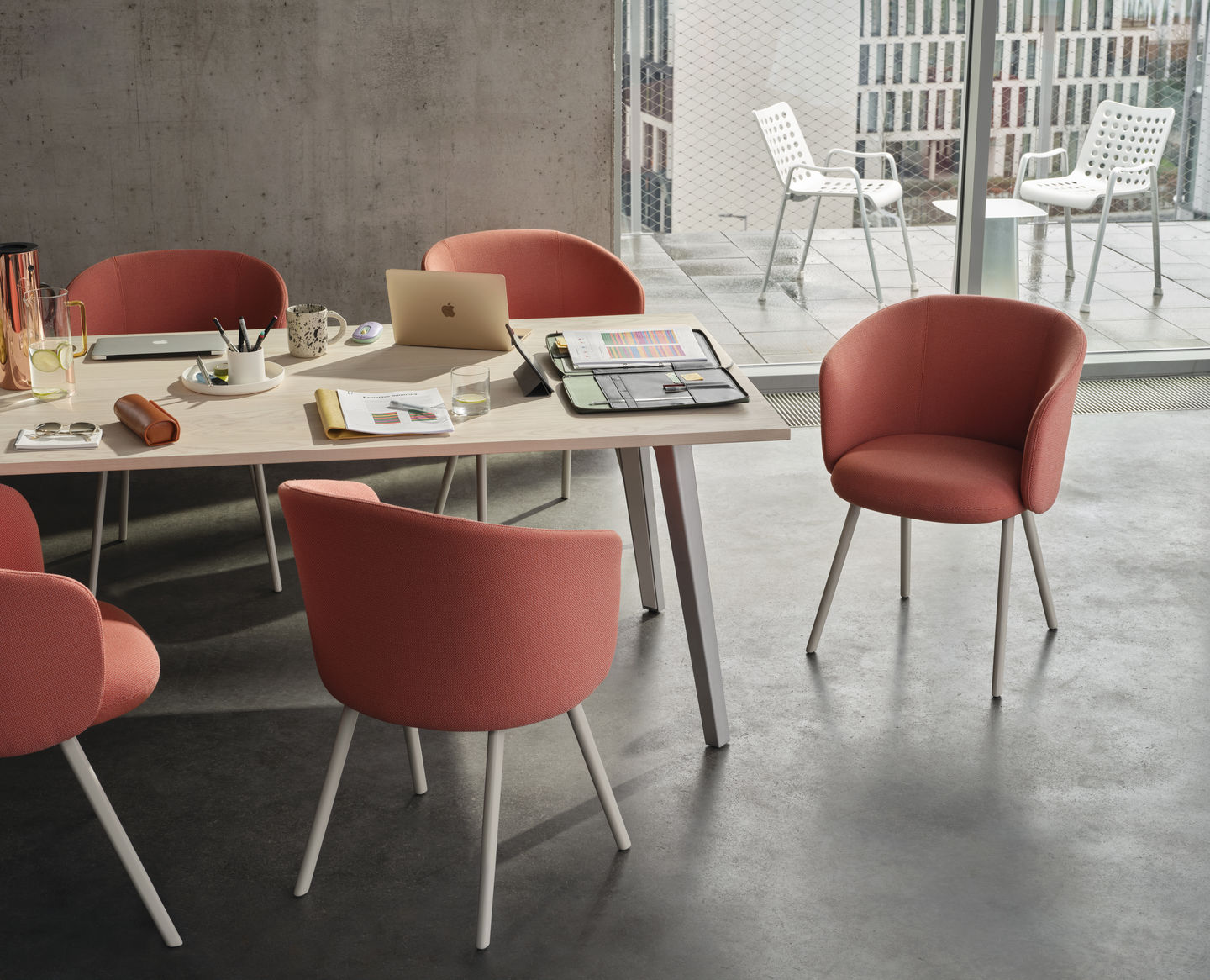 Vitra Mikado Armlehnstuhl in Koralle an einem Konferenztisch, moderner Stuhl für Büro und Wohnraum.