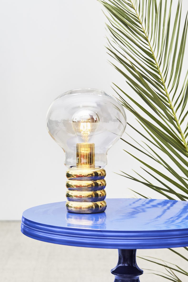 Ingo Maurer Bulb Tischleuchte aus Messing und Glas auf blauem Tisch, modernes Design.