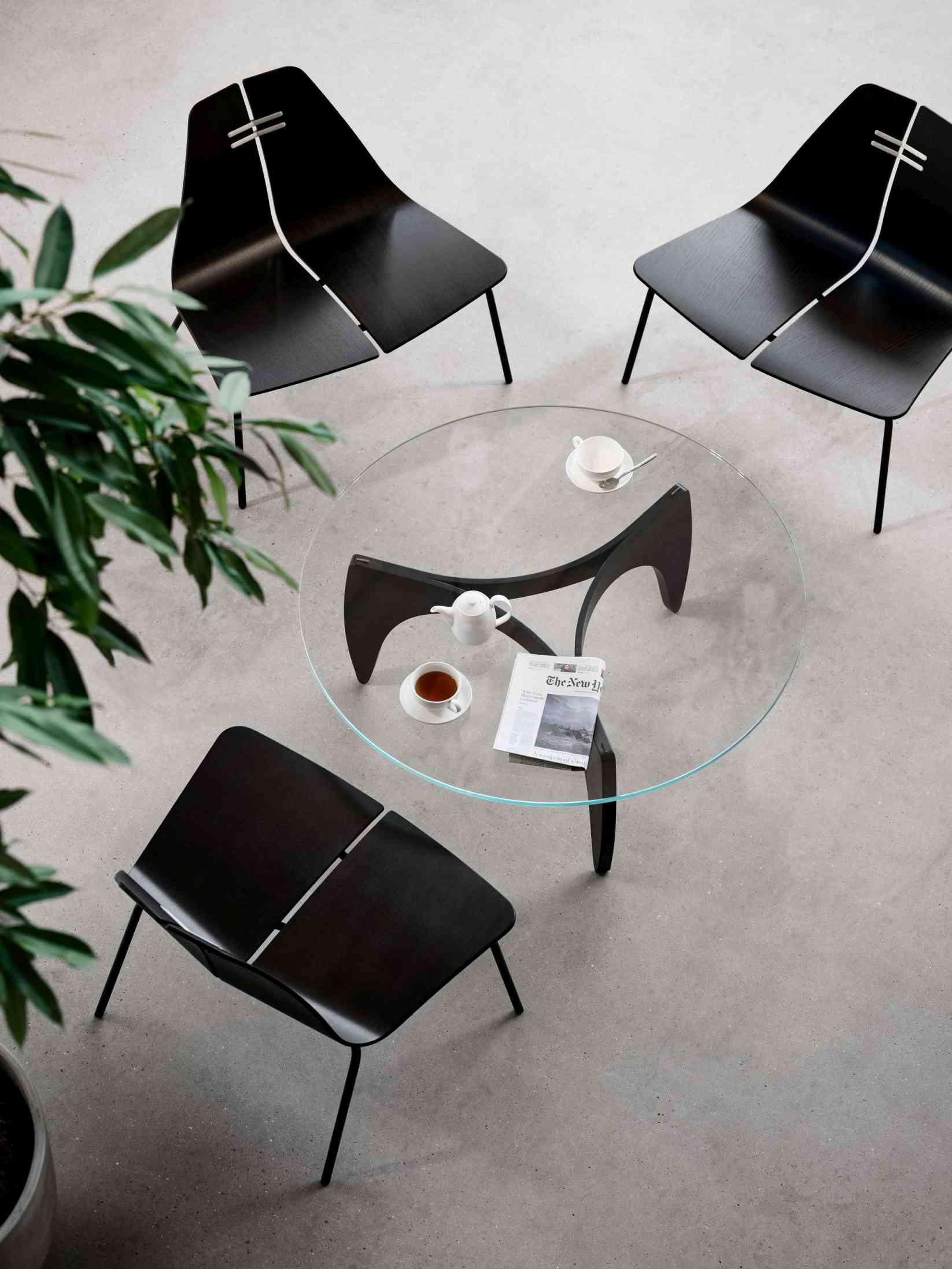 Drei PK23 Loungesessel von Fritz Hansen um einen runden Glastisch, modernes Möbeldesign.