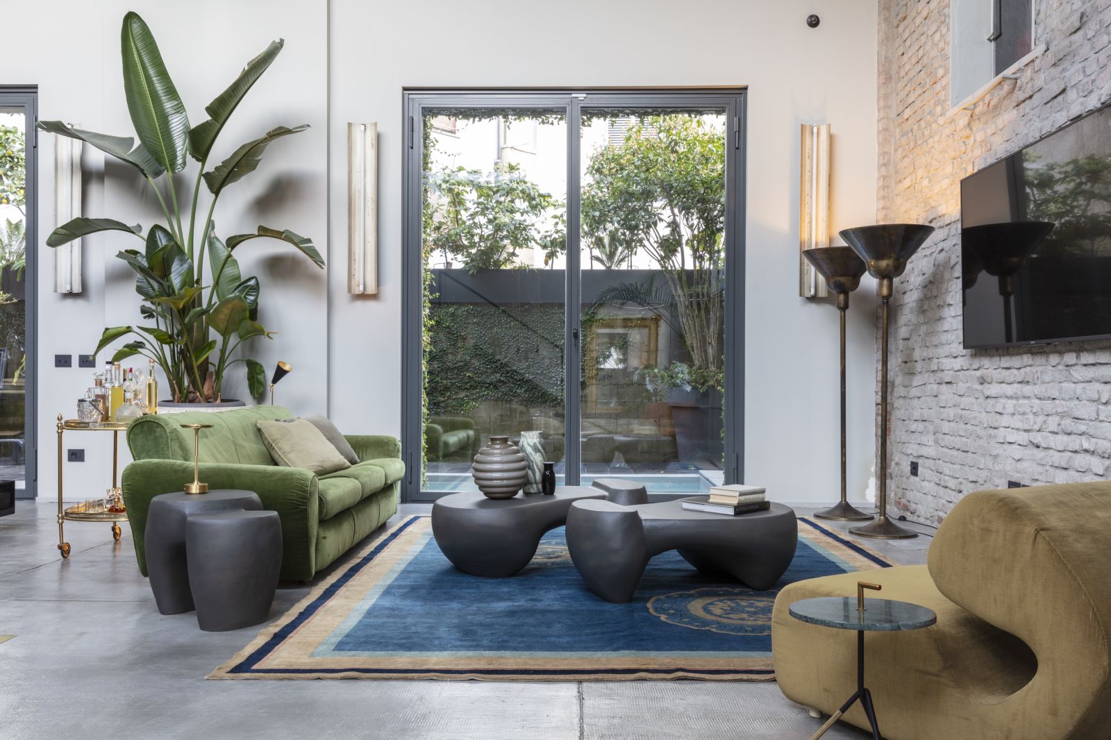 Wohnzimmer mit Mogg Couchtisch Dune, Teppich, Sofa und Blick in den Garten.