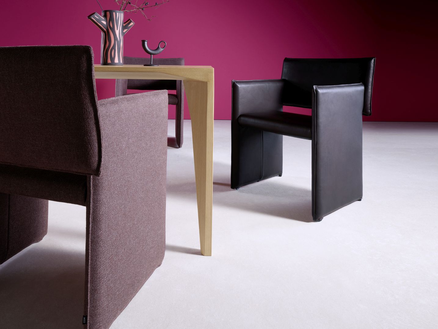 Nahaufnahme von zwei Cor Noto Stühlen, einer aus Stoff, einer aus Leder, am Esstisch.