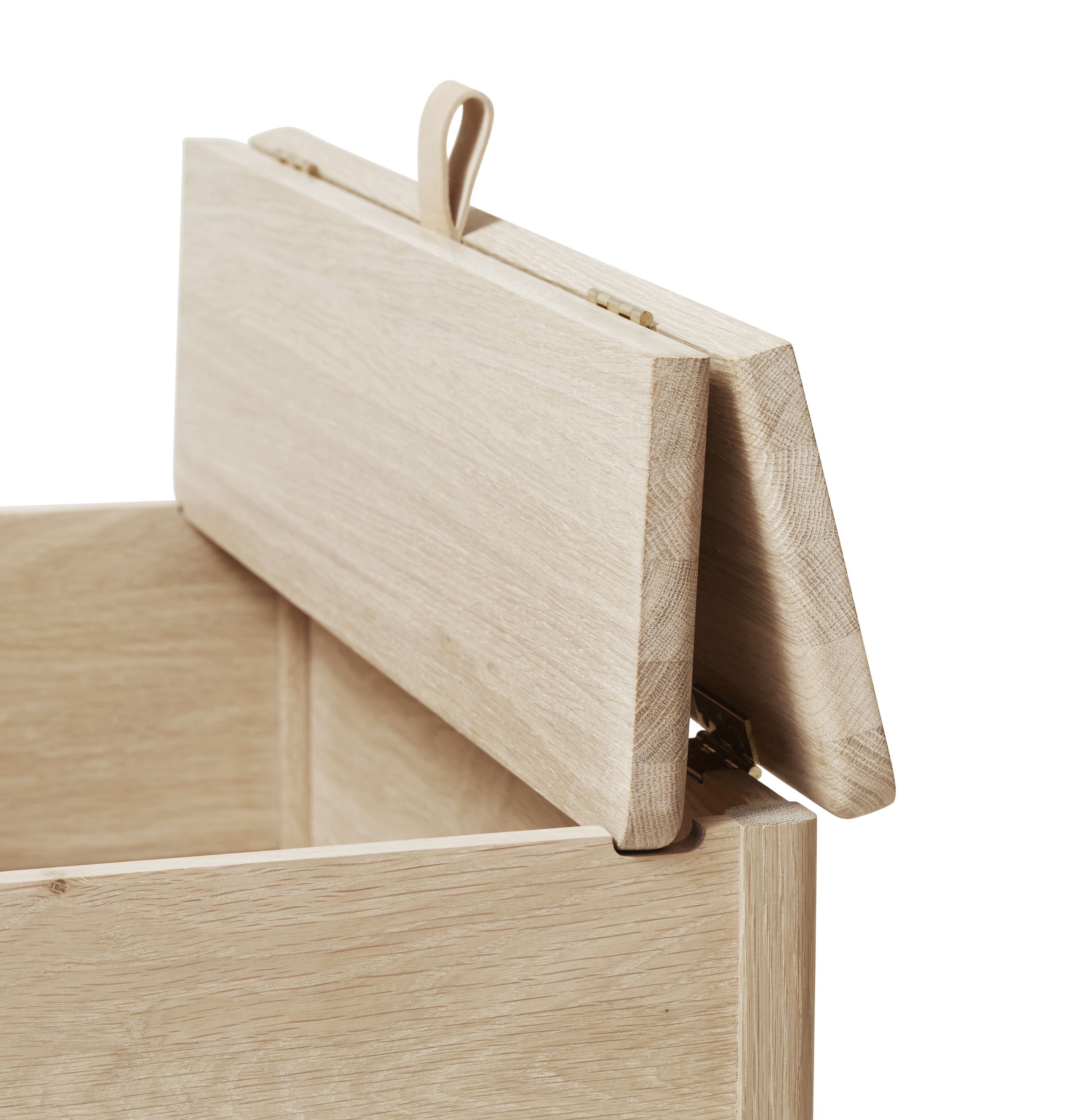 A Line Truhenbank aus Eiche, weiß geölt, mit geöffnetem Deckel und Ledergriff.