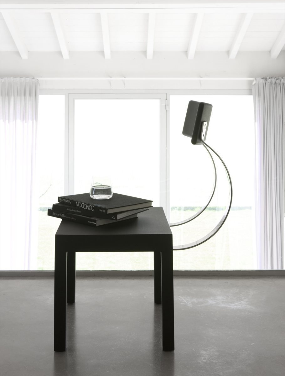 Schwarzer Follia Stuhl von Zanotta, minimalistisches Design, neben einem schwarzen Tisch mit Büchern und Wasserglas.