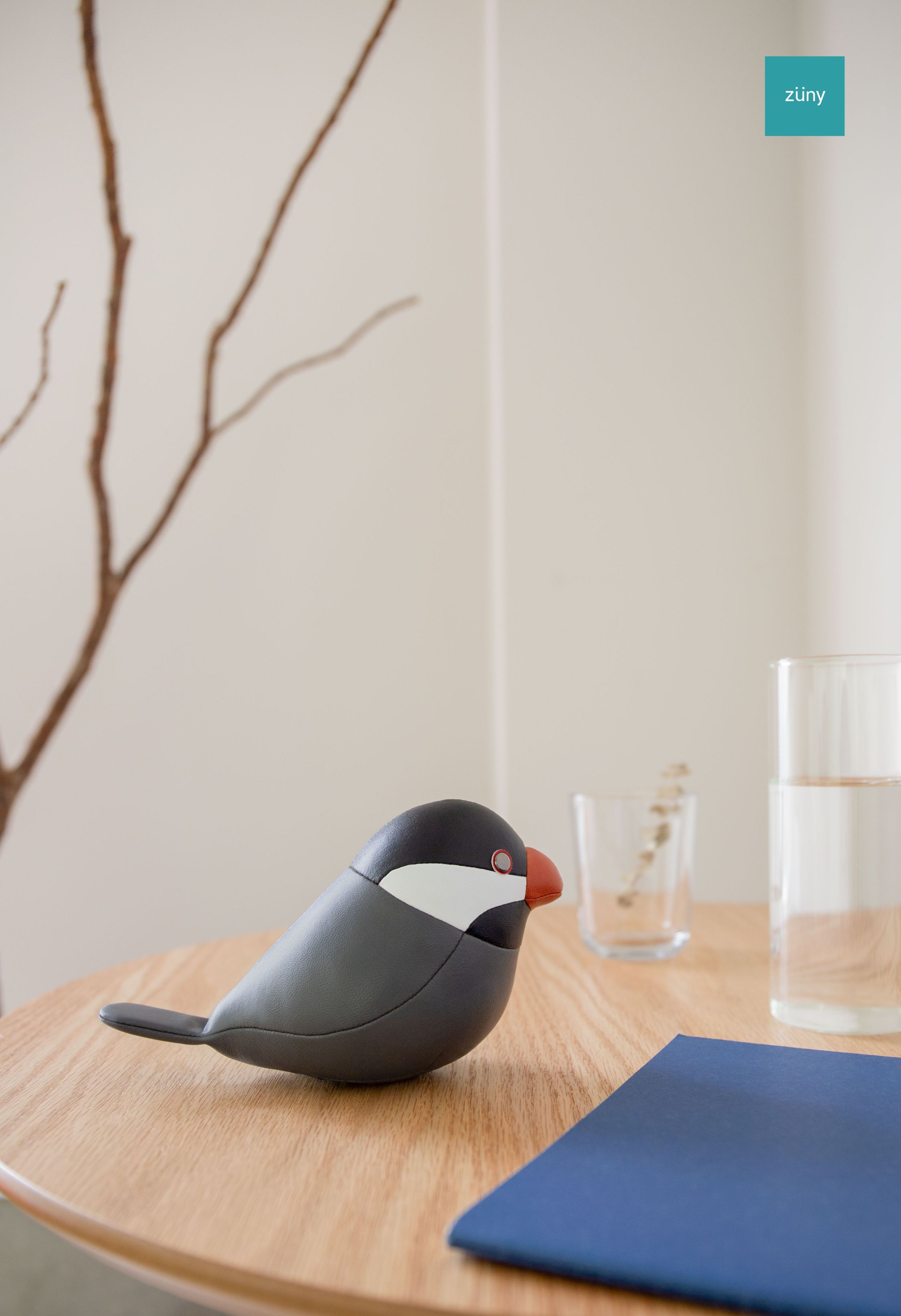 Nahaufnahme des schwarzen Java Spatz Briefbeschwerers von Züny auf einem Holztisch. Dekorative Büroaccessoires.